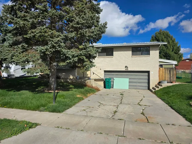 View of front of property with a front lawn, a garage, concrete driveway, and brick siding