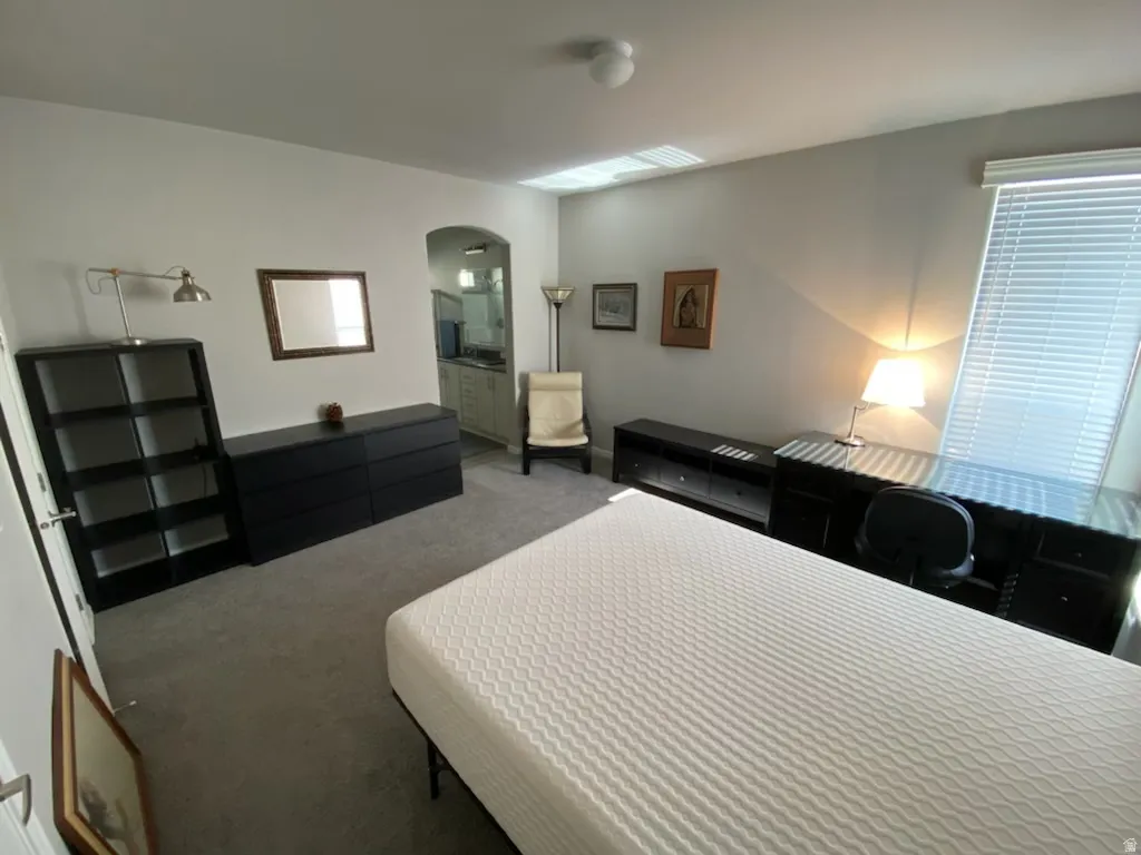 Bedroom with arched walkways, carpet floors, and ensuite bathroom
