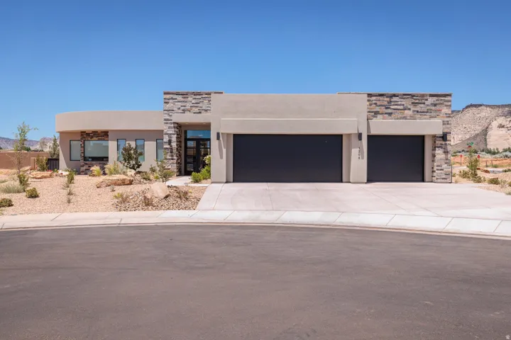 View of front of house featuring stone siding, stucco siding, an attached garage, concrete driveway, and a mountain view