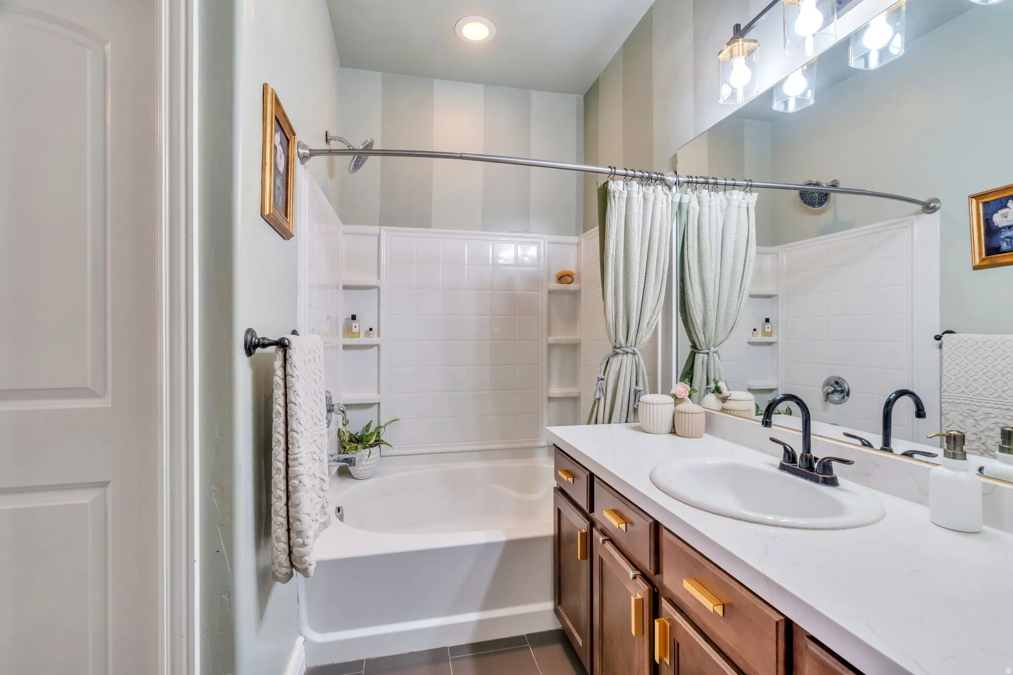 Bathroom with vanity, shower / bath combination with curtain, and dark tile patterned flooring