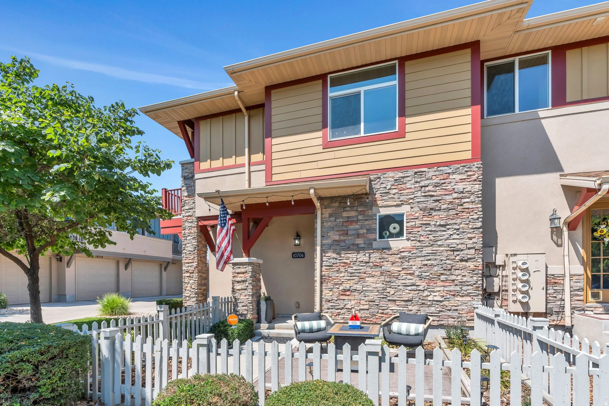 View of front of home featuring a balcony, a fenced front yard, stone siding, a garage, and driveway