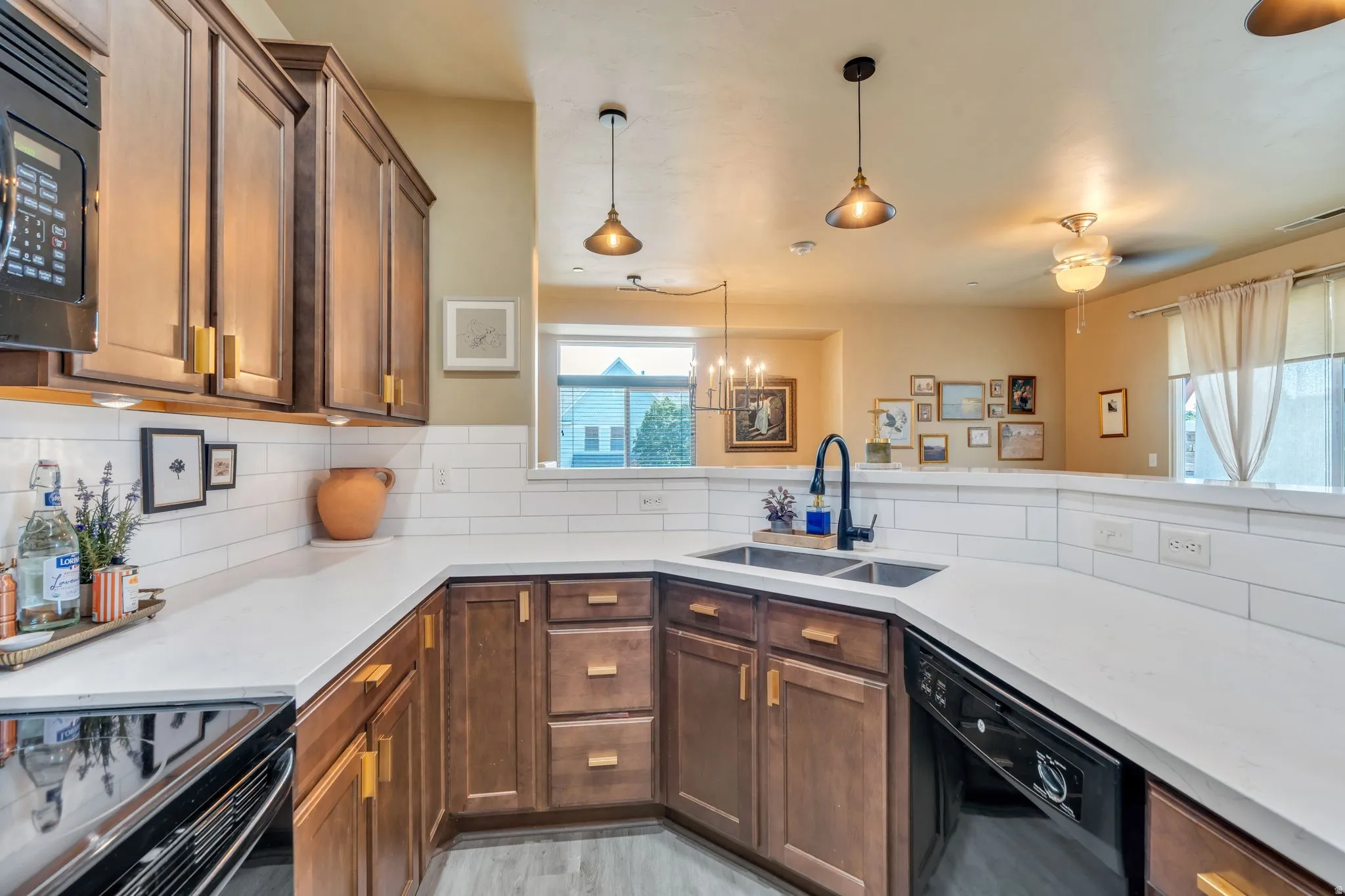 Kitchen with black appliances, tasteful backsplash, light stone counters, and wood finish cabinetry