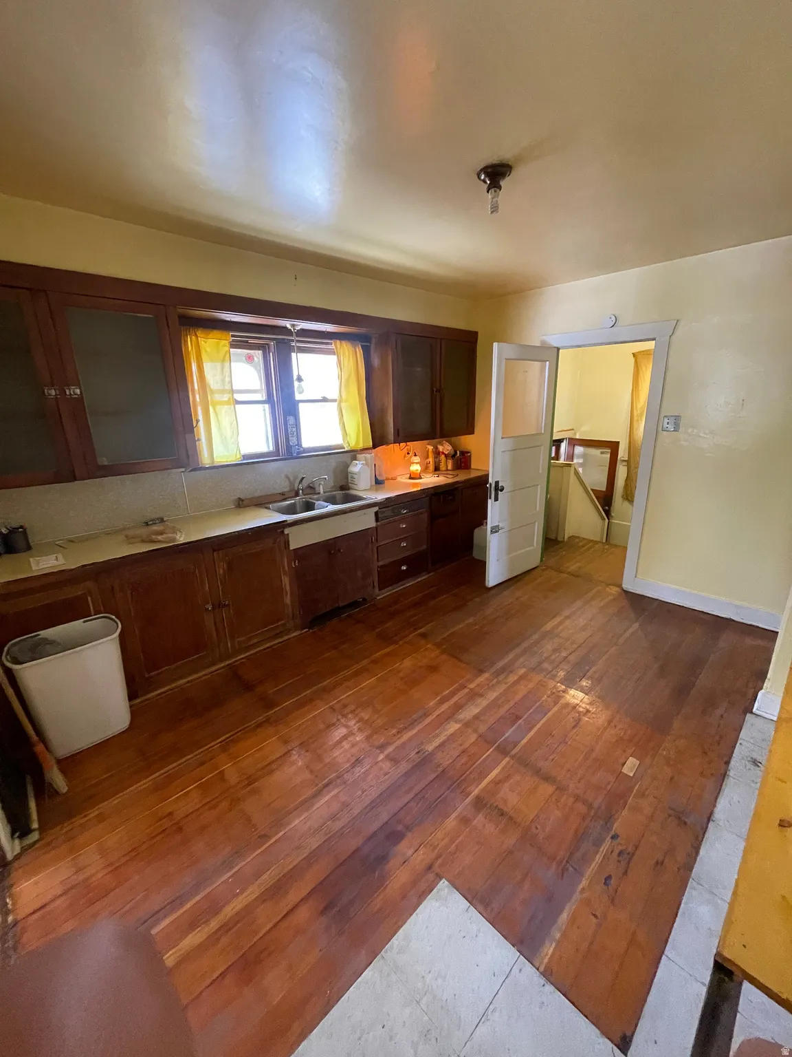 Kitchen with glass fronted cabinets, dark wood finished floors, light countertops, and wood finish cabinetry