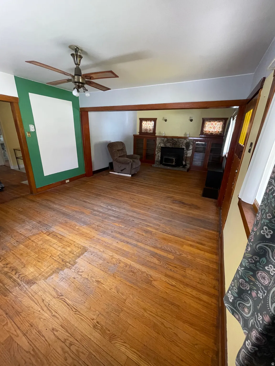 Unfurnished living room featuring light wood-style flooring, ceiling fan, and a fireplace