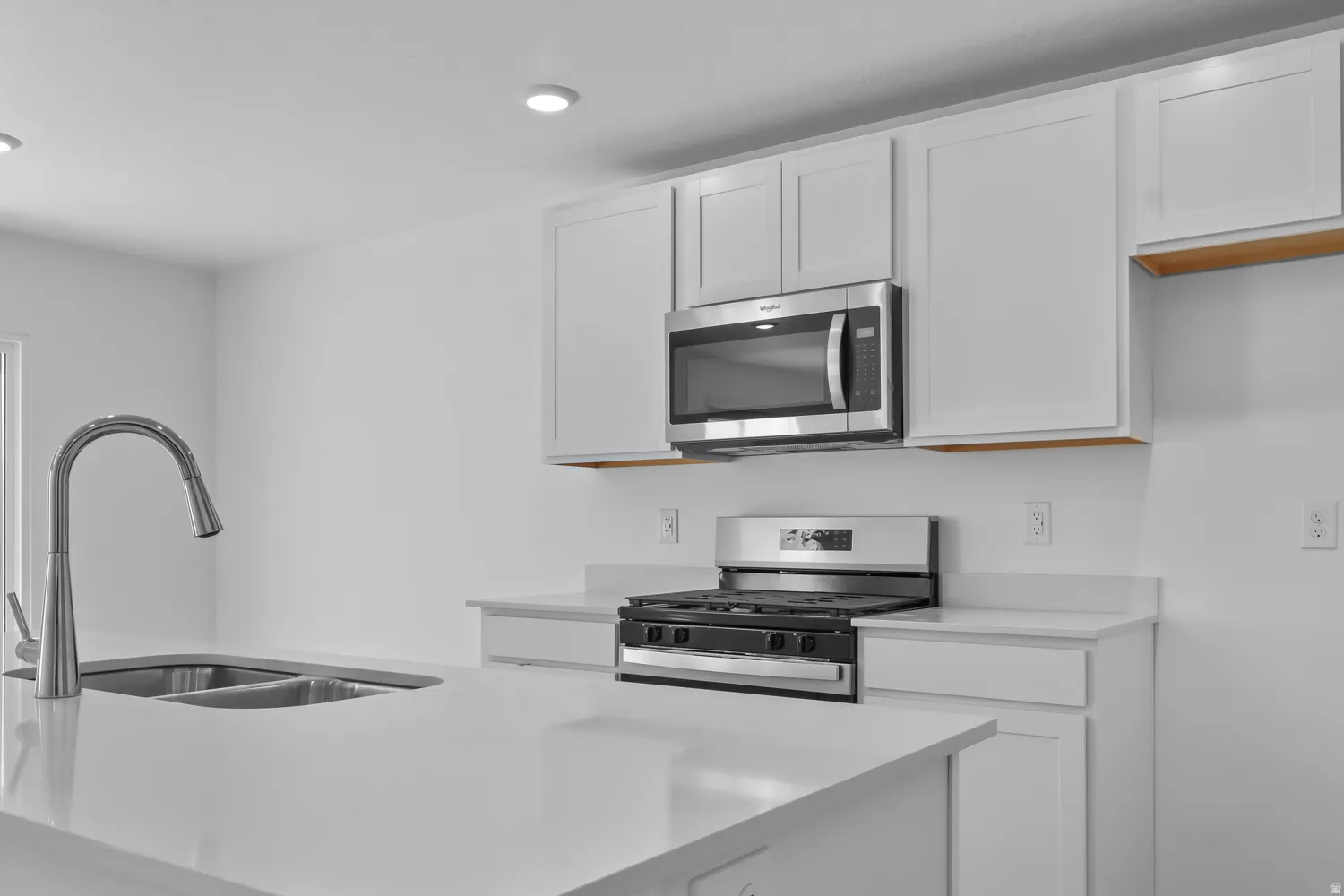 Kitchen with stainless steel appliances, white cabinets, a kitchen island with sink, and recessed lighting
