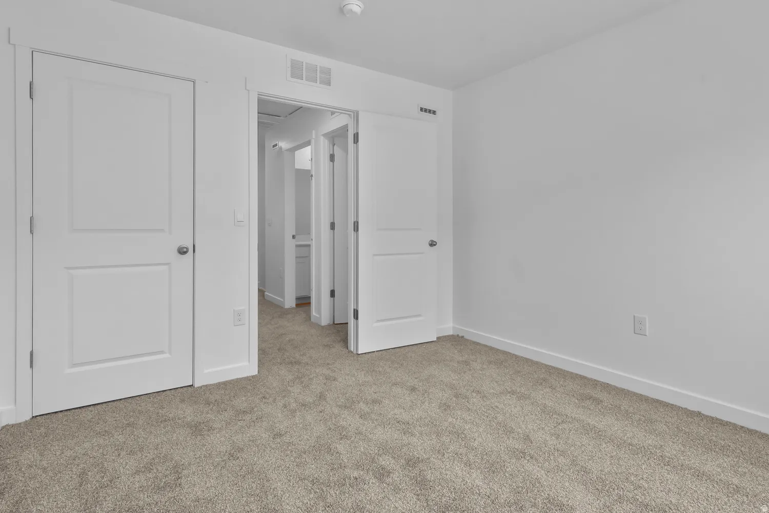 Unfurnished bedroom with light carpet and baseboards