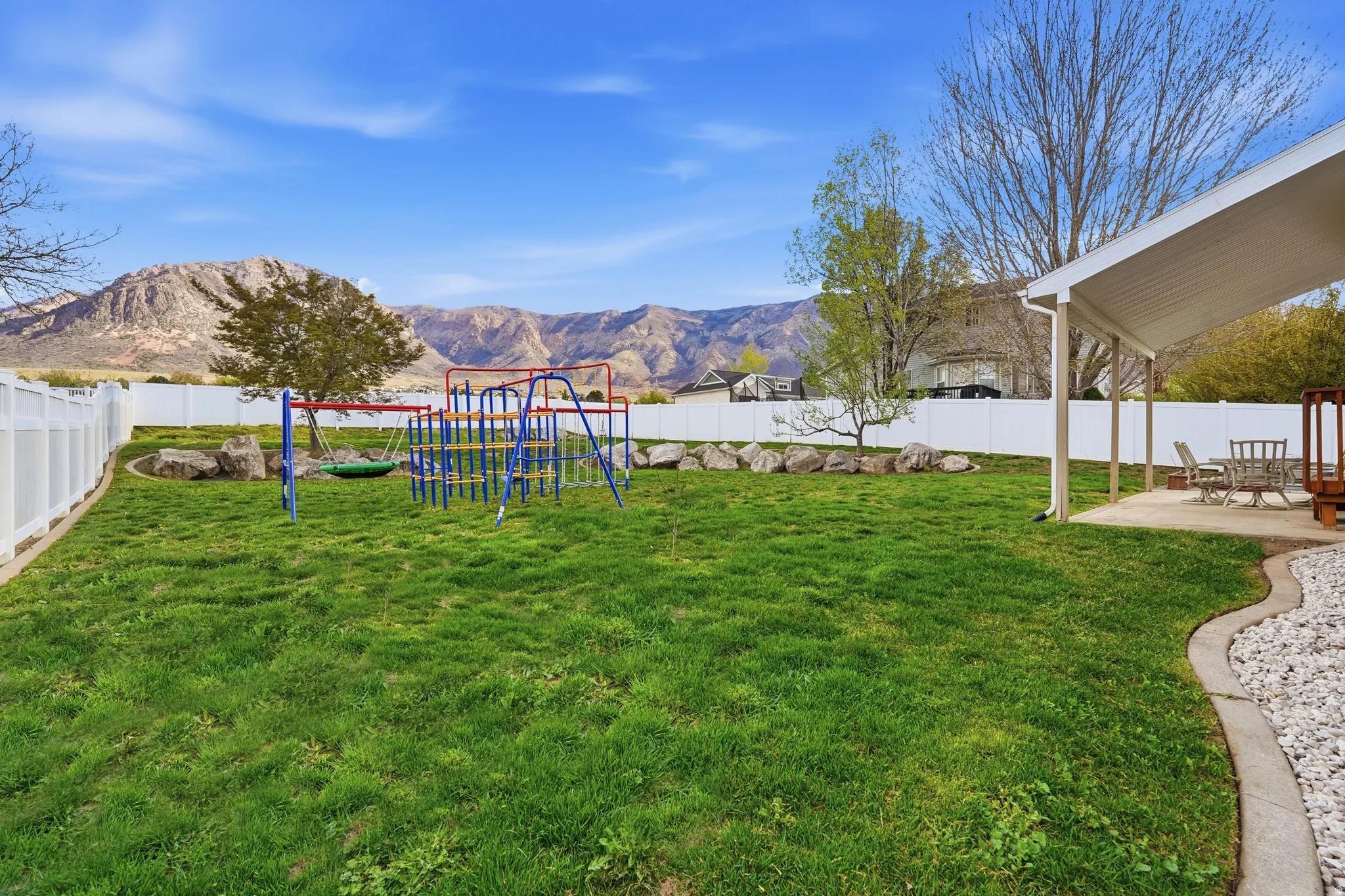 Fenced backyard featuring a mountain view, a playground, and a patio