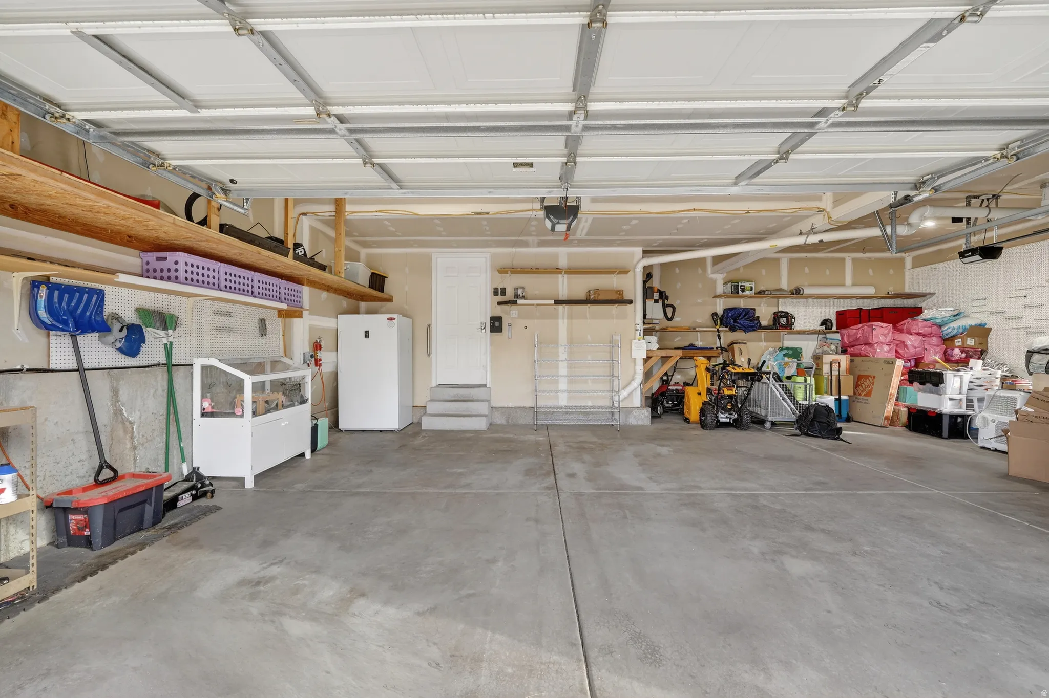 Garage with freestanding refrigerator and a garage door opener