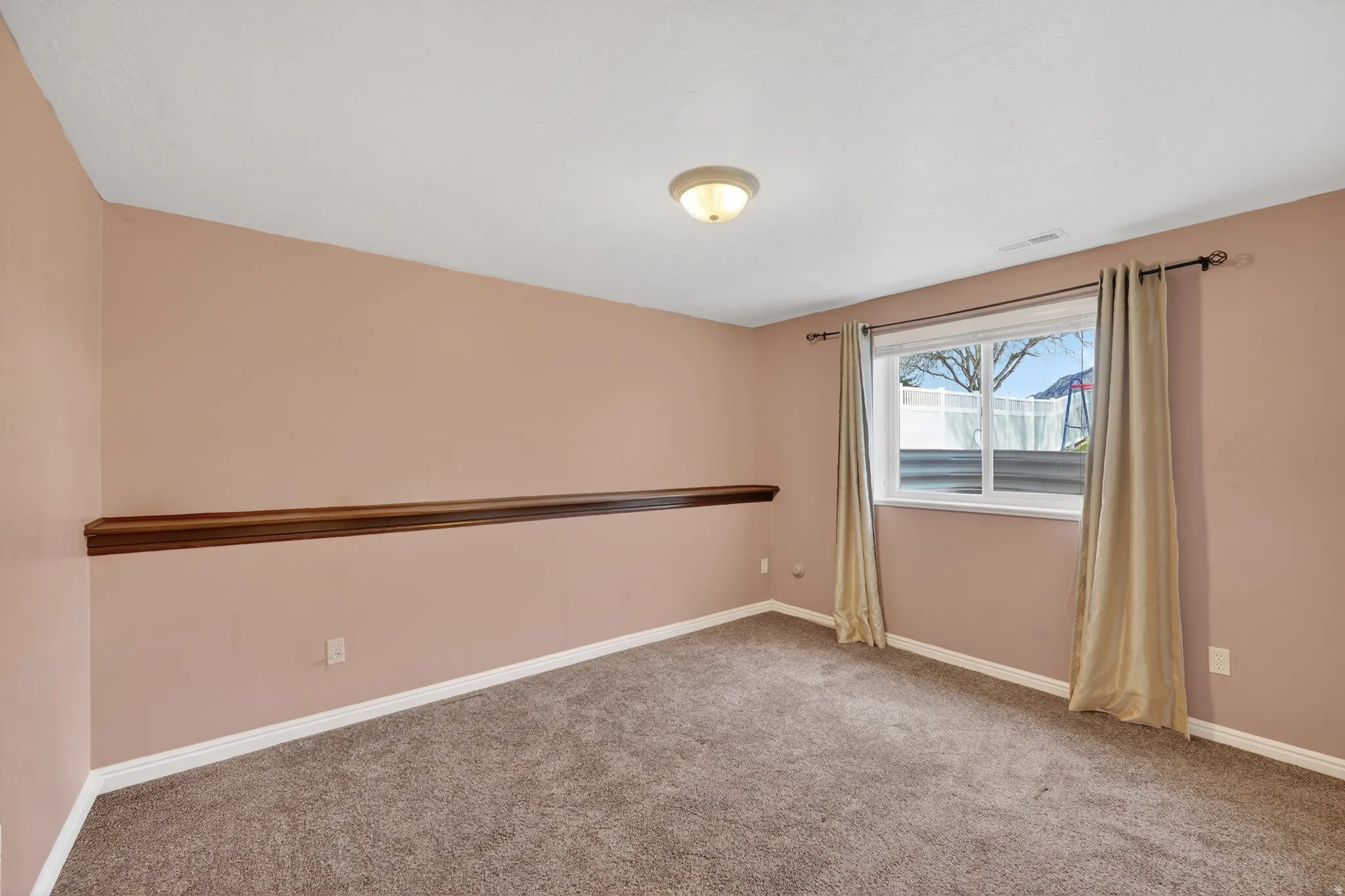 Empty room with light colored carpet and baseboards
