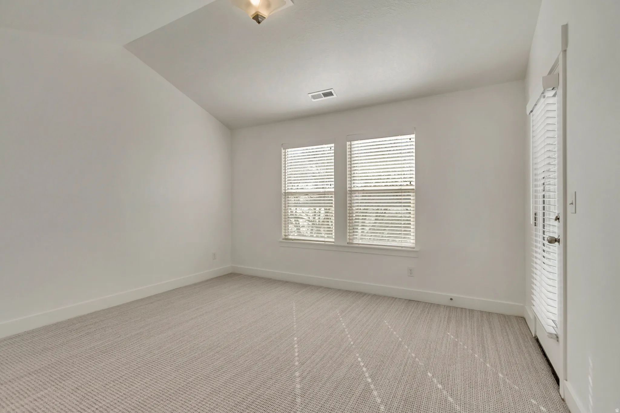 Spare room with light colored carpet and lofted ceiling