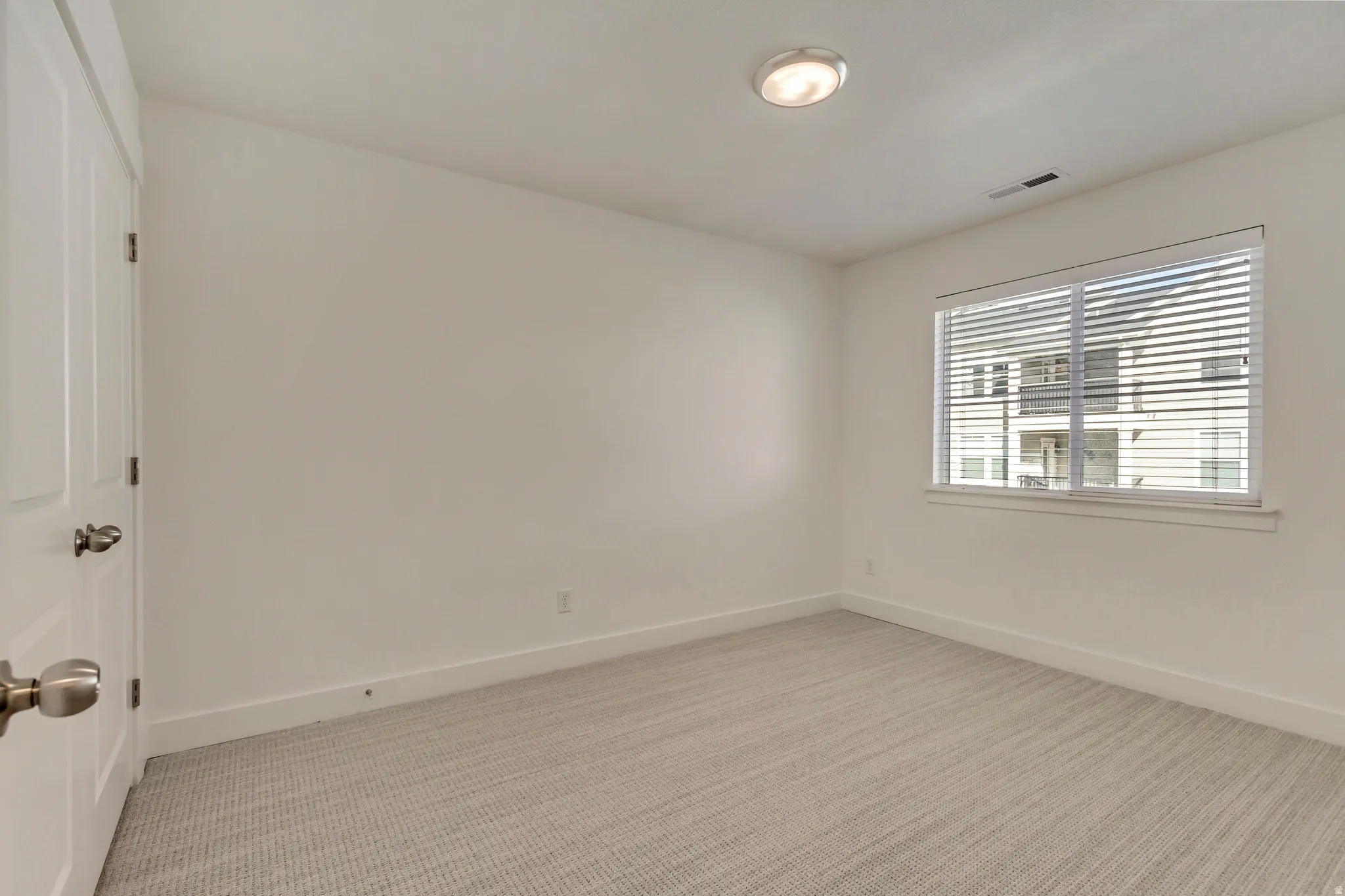 Empty room featuring light colored carpet and baseboards