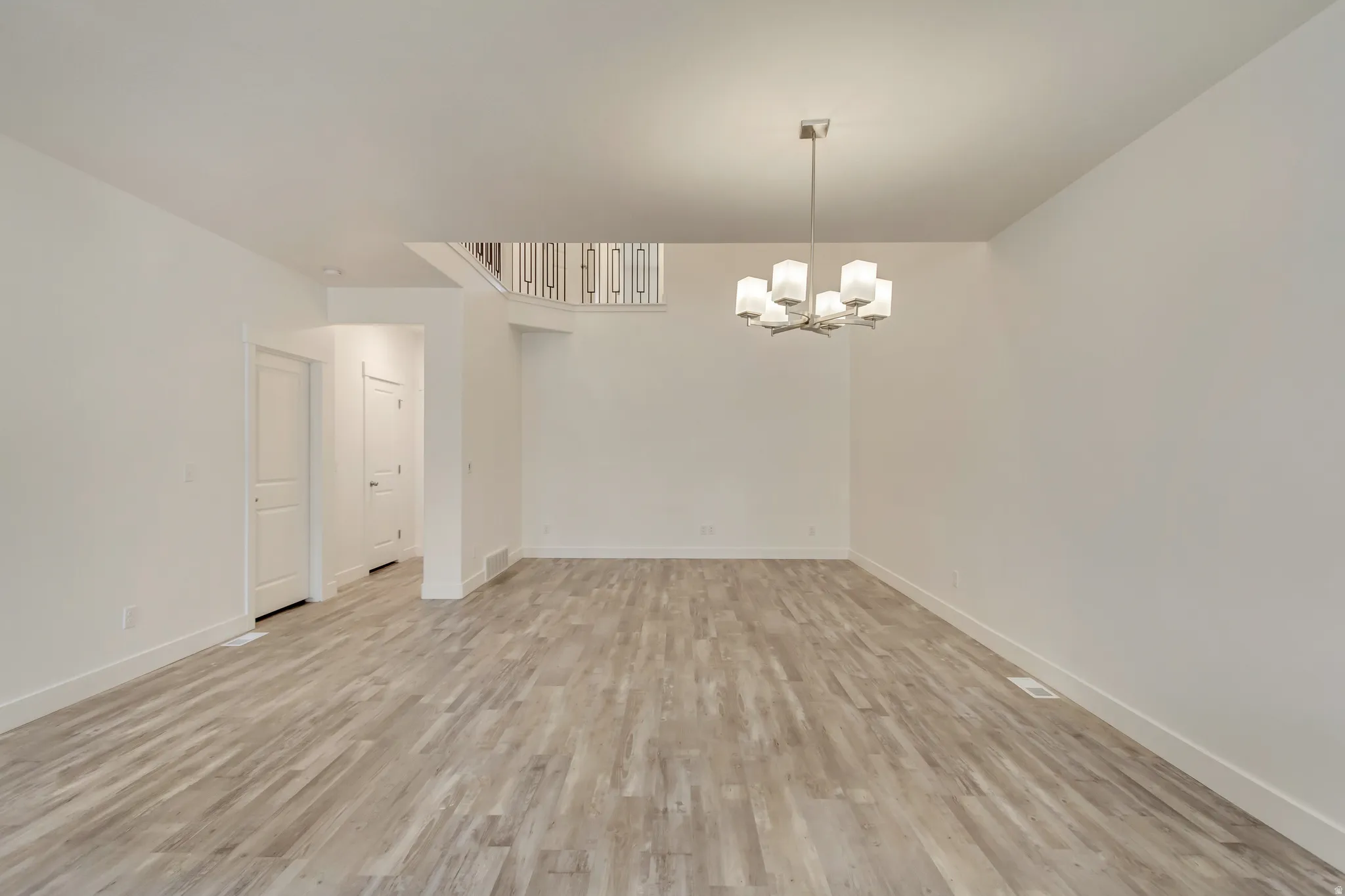 Spare room featuring light wood-type flooring and hanging lights