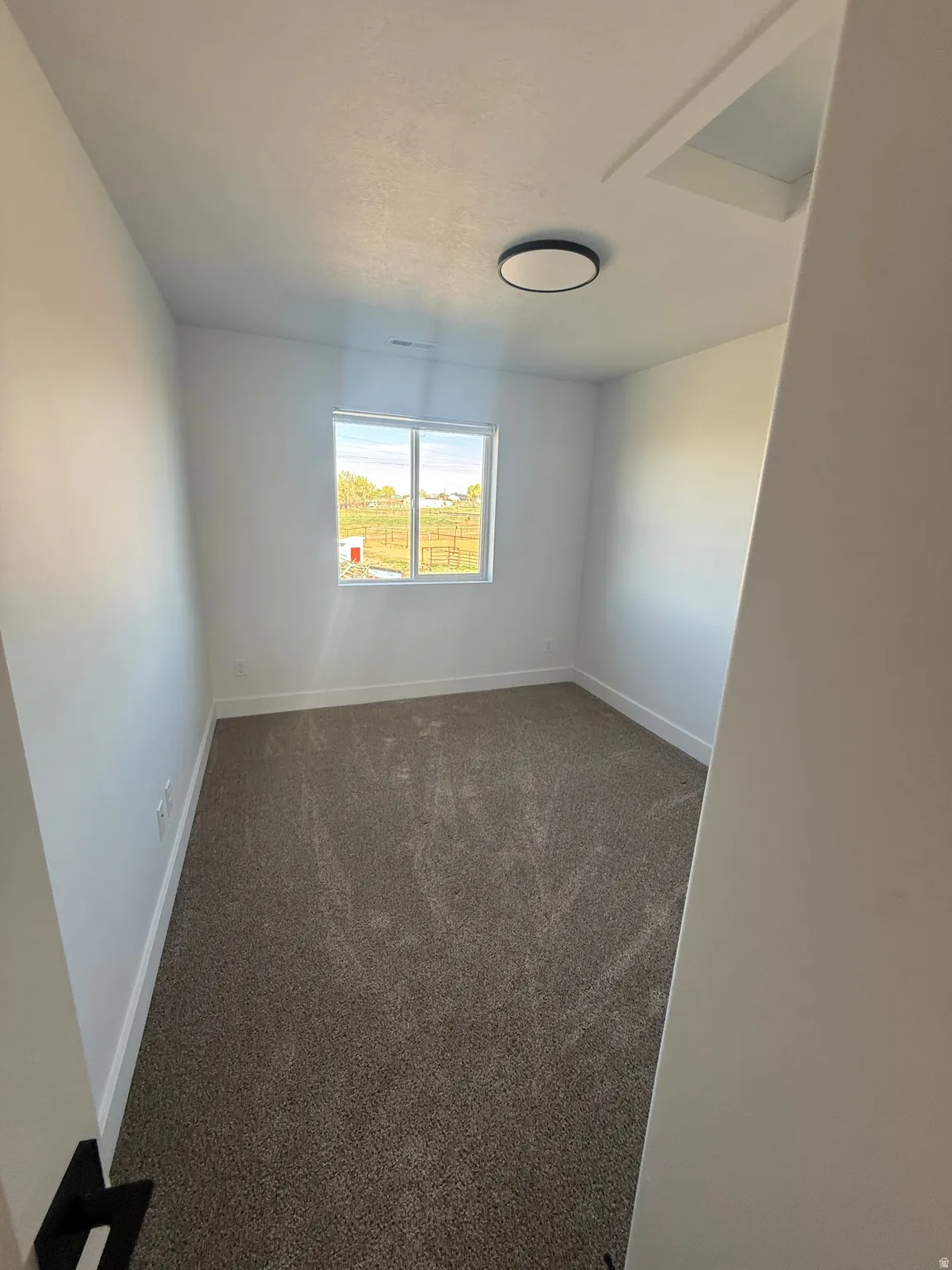 Empty room with dark colored carpet and baseboards