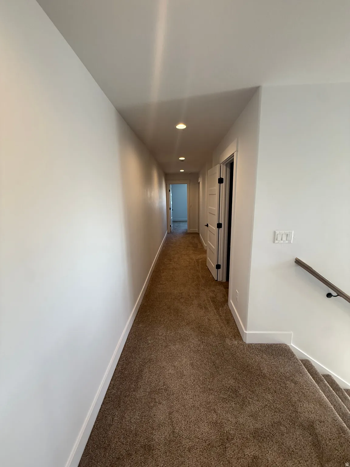 Corridor featuring dark colored carpet, recessed lighting, and an upstairs landing