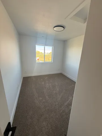 Empty room with dark colored carpet and baseboards
