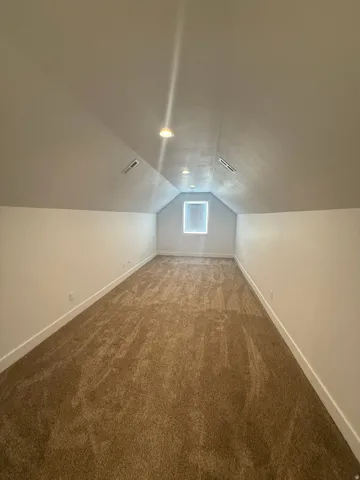 Bonus room with baseboards and dark carpet