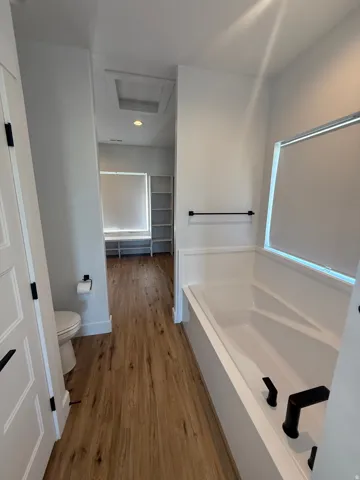 Full bath featuring a bath and light wood-type flooring