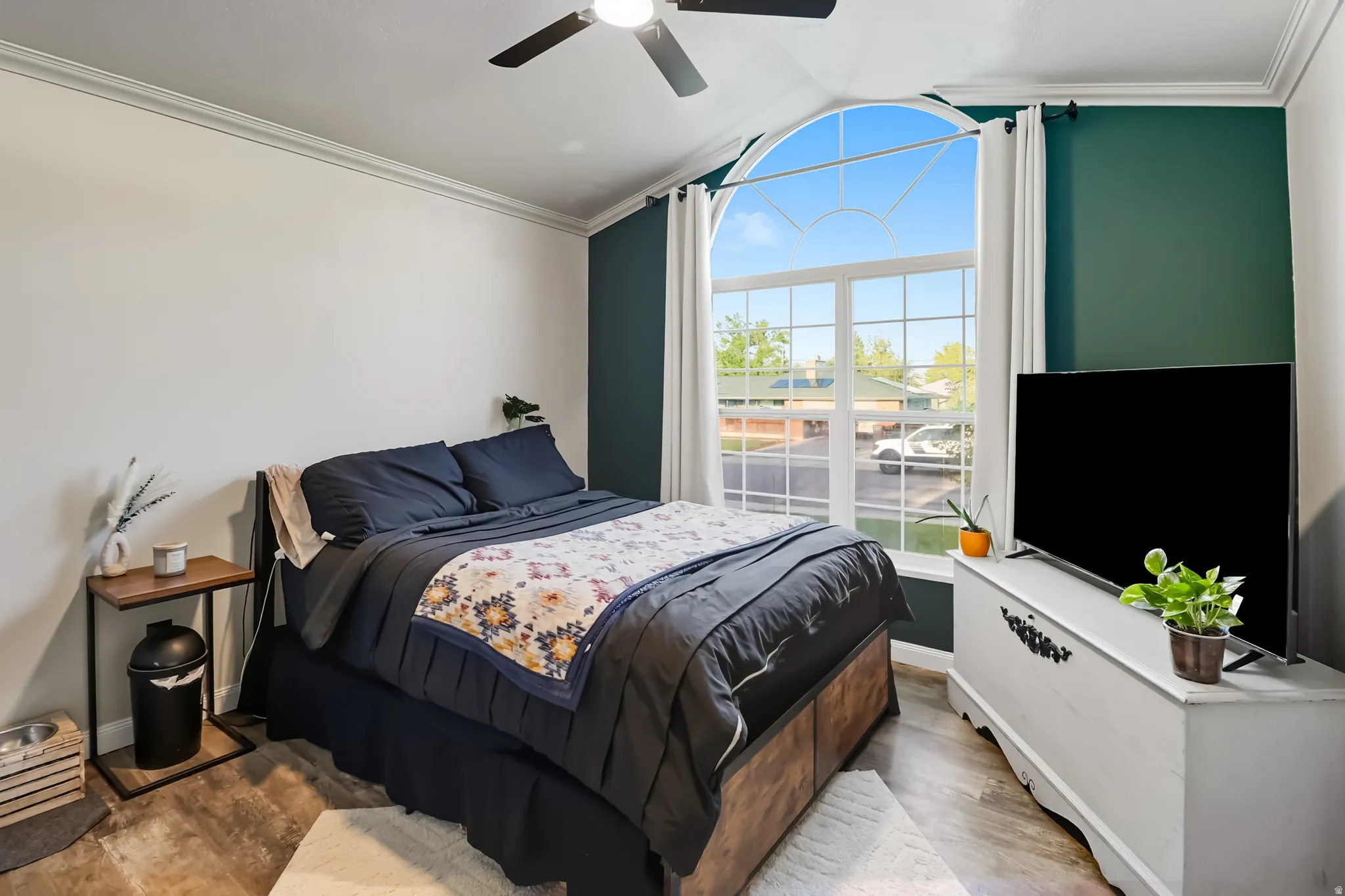 Bedroom with crown molding, wood finished floors, and a ceiling fan