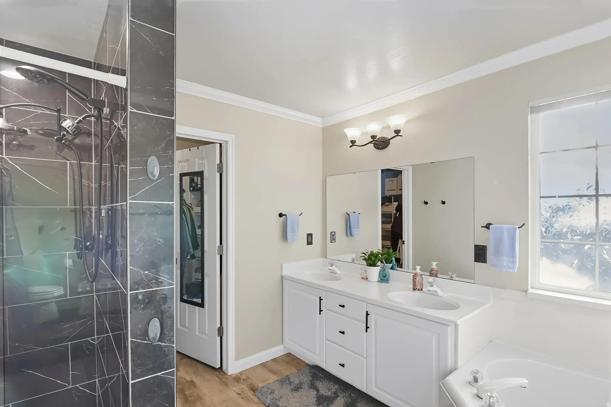 Master Bathroom with ornamental molding, double vanity, a stall shower, light wood-style floors, and a bath