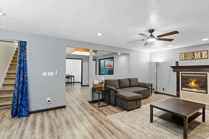 Basement living area with a tile fireplace, light wood finished floors, ceiling fan, a textured ceiling, and recessed lighting