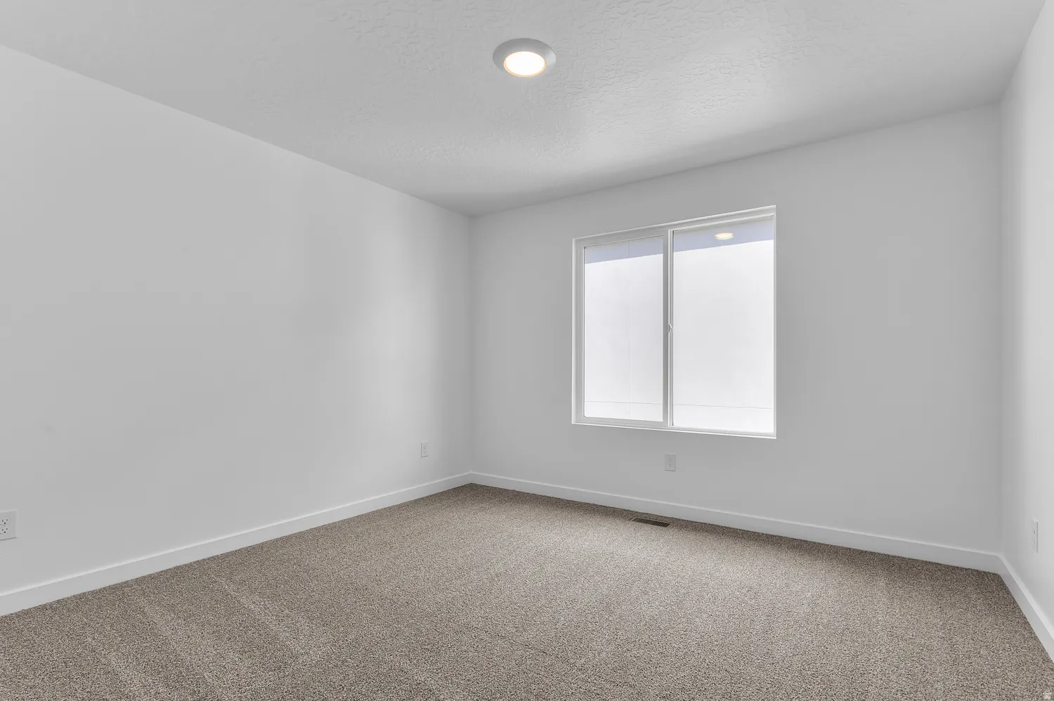 Empty room with carpet floors and a textured ceiling
