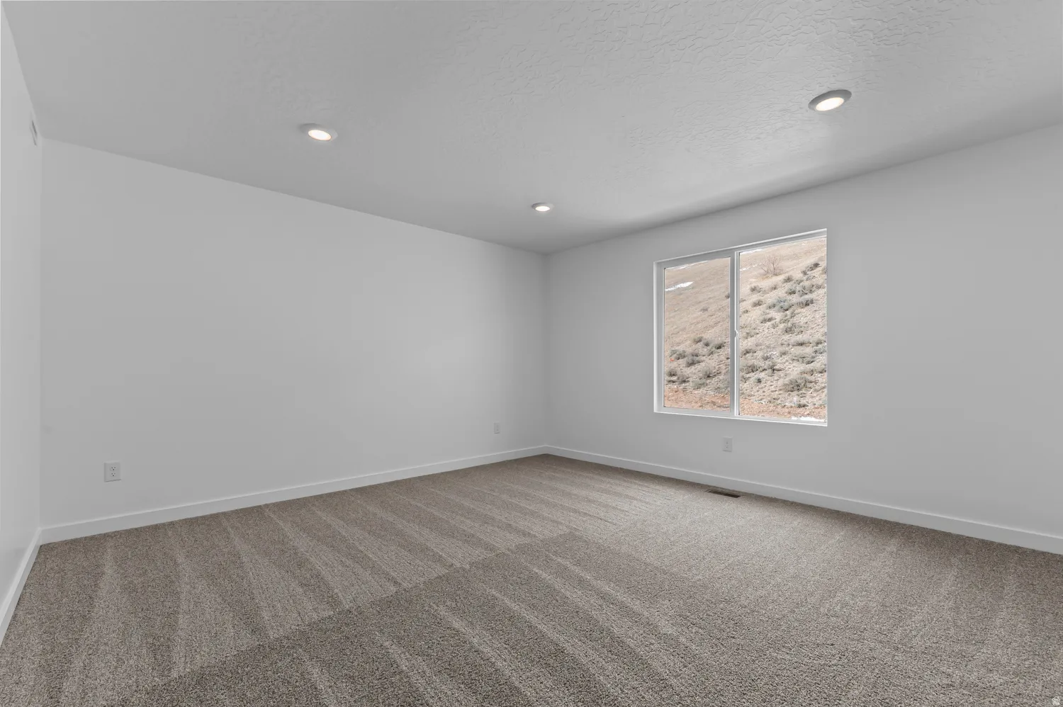 Empty room with light colored carpet, recessed lighting, and a textured ceiling