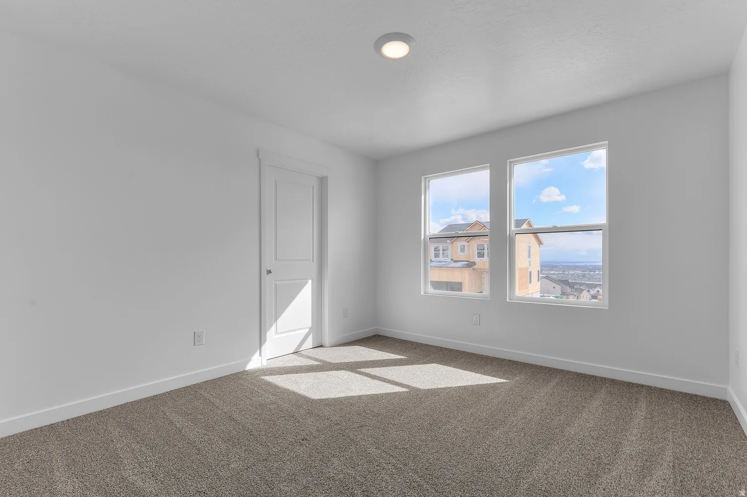 Carpeted spare room featuring baseboards
