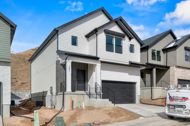 View of front of property featuring a garage, driveway, and brick siding