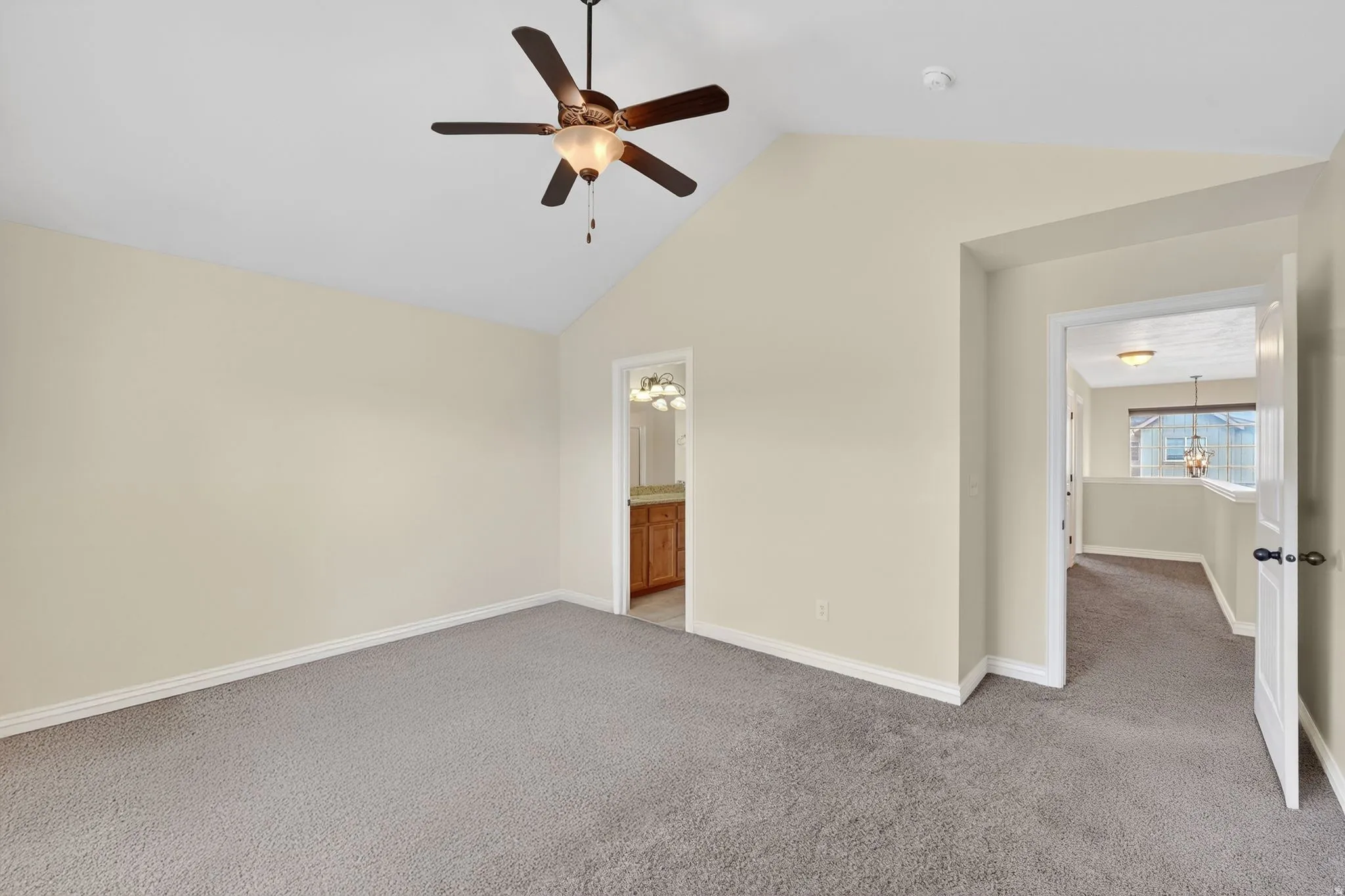 Unfurnished bedroom with light carpet, a ceiling fan, ensuite bath, and a high ceiling