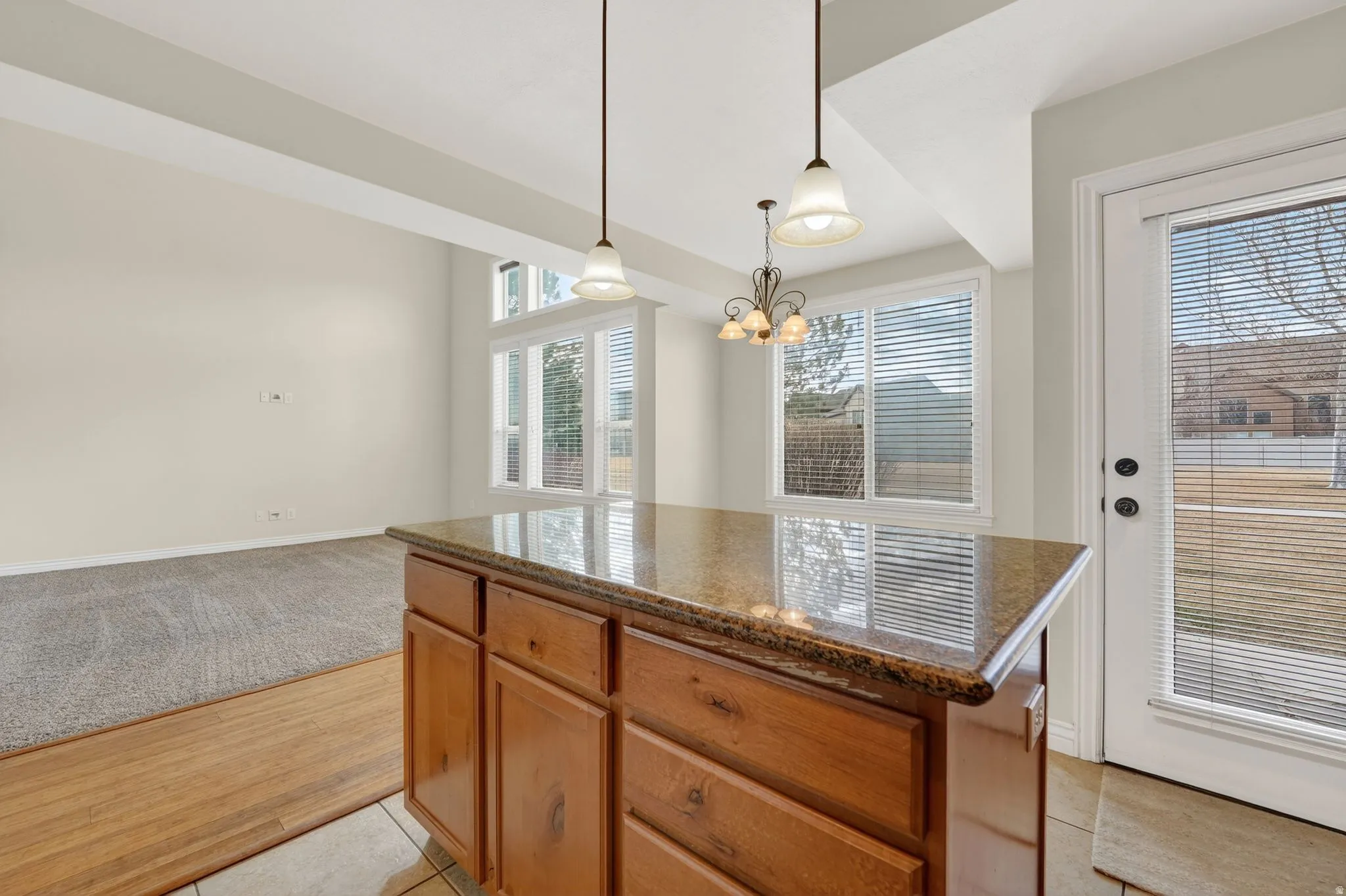 Kitchen featuring a center island, dark stone counters, wood finish cabinets, light wood-style floors, and a chandelier