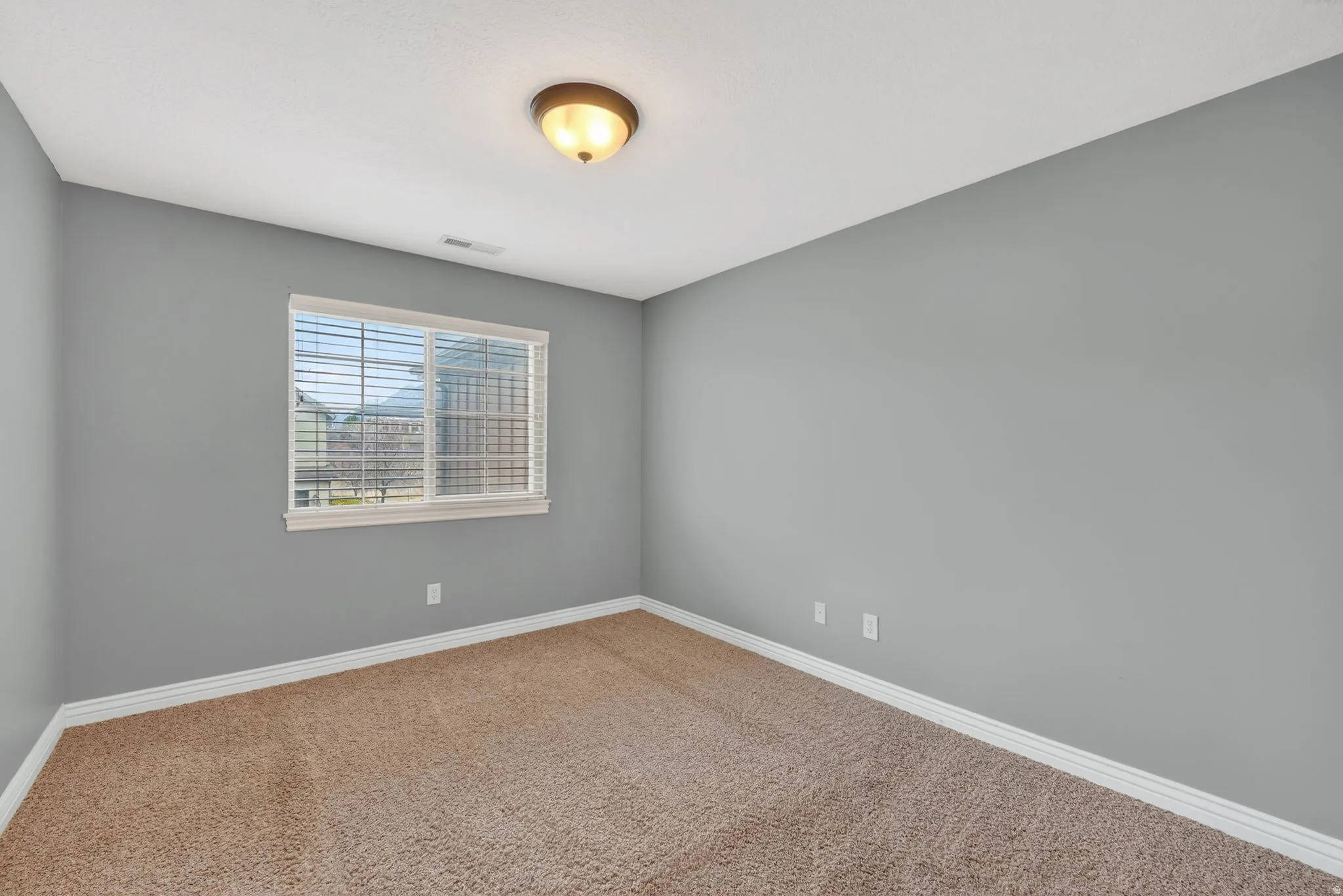 Carpeted spare room featuring baseboards