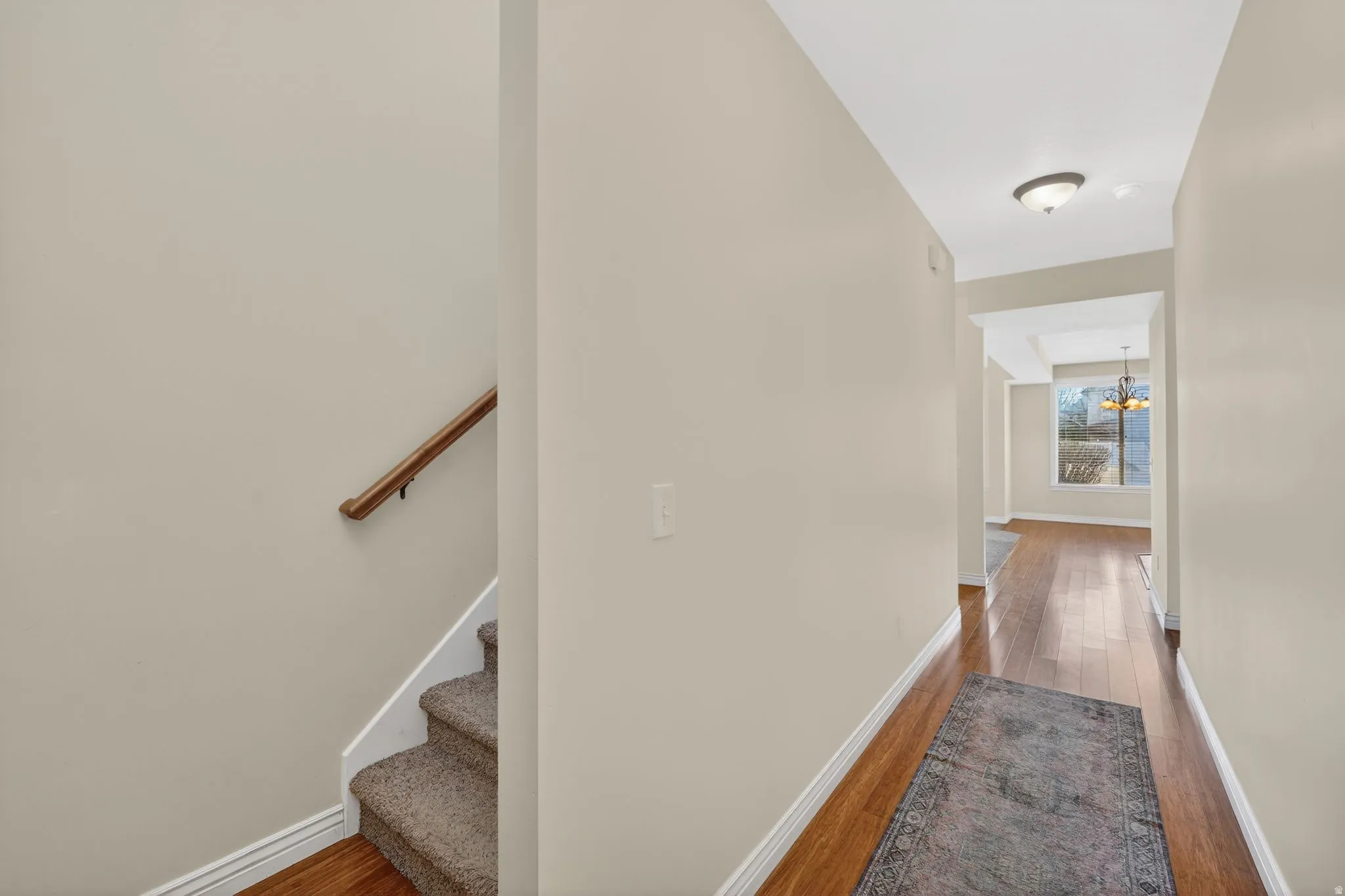Corridor with dark wood-style flooring and a chandelier