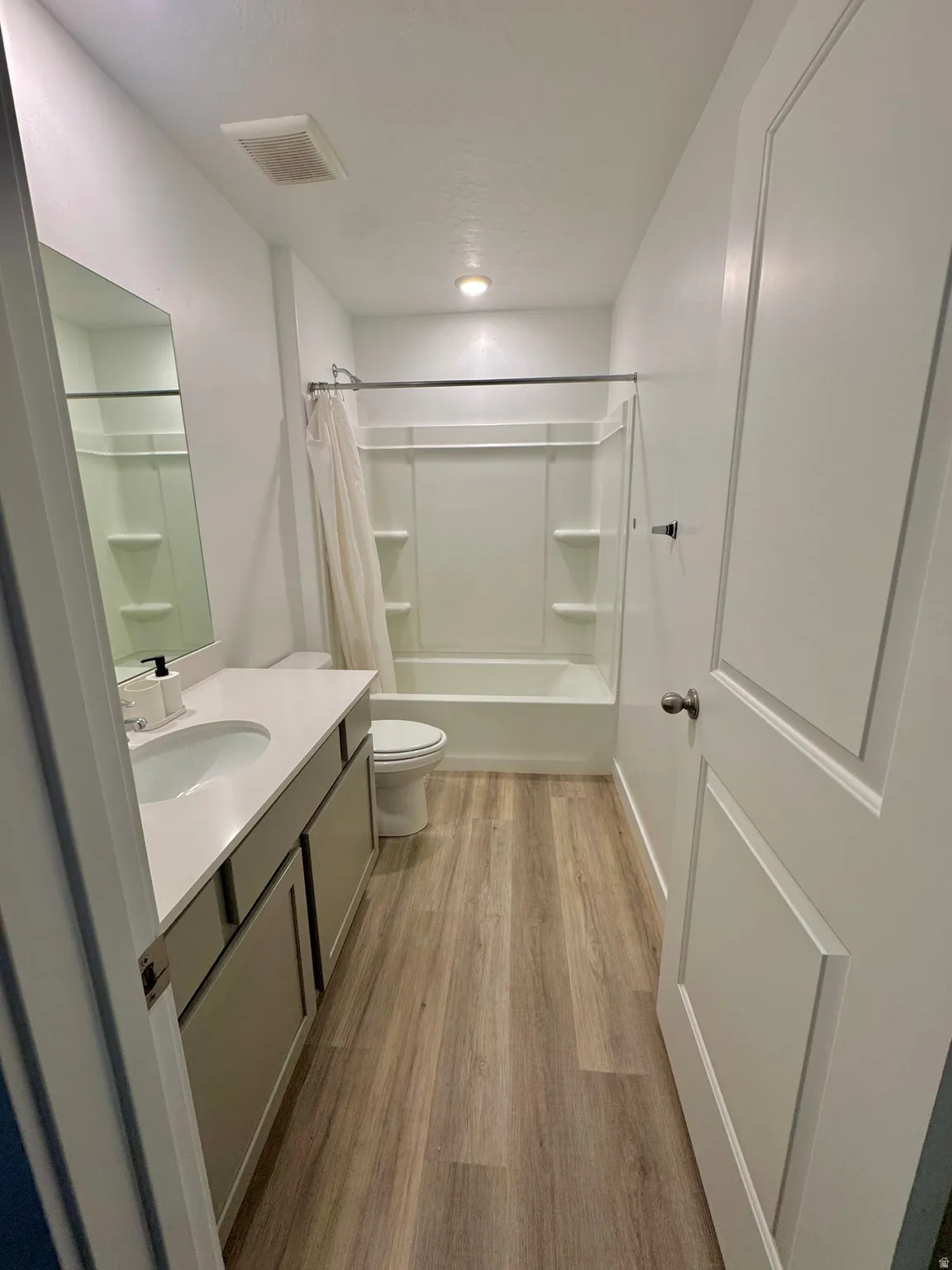 Bathroom featuring vanity, light wood-style flooring, and shower / bath combination with curtain