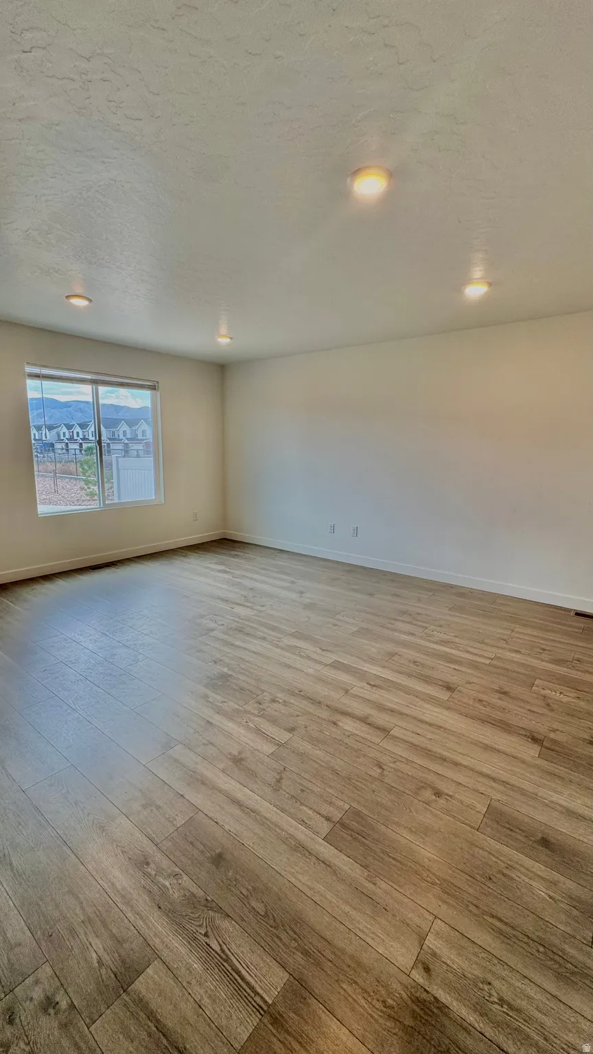 Empty room with a textured ceiling and light wood finished floors
