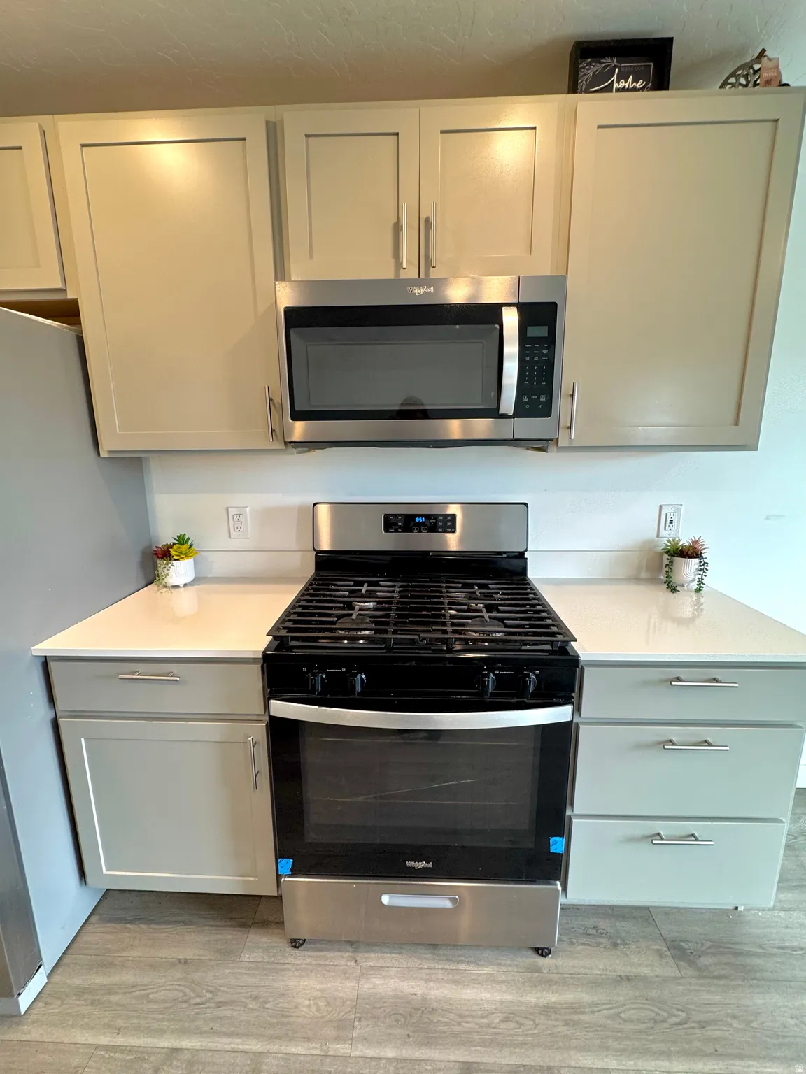 Kitchen with stainless steel appliances, light wood-style floors, and gray cabinets