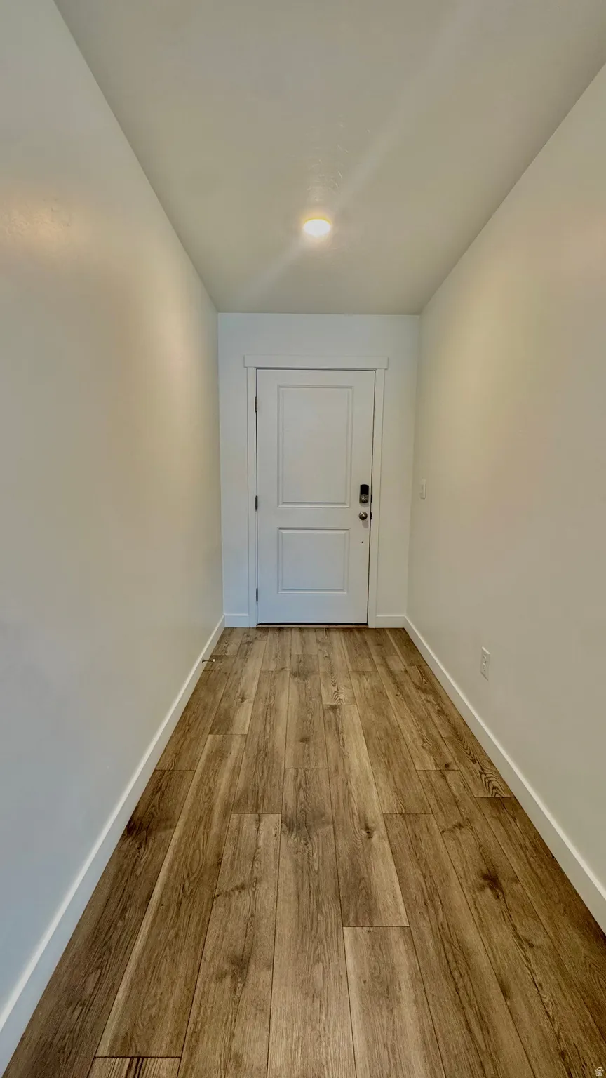 Doorway with wood finished floors and baseboards
