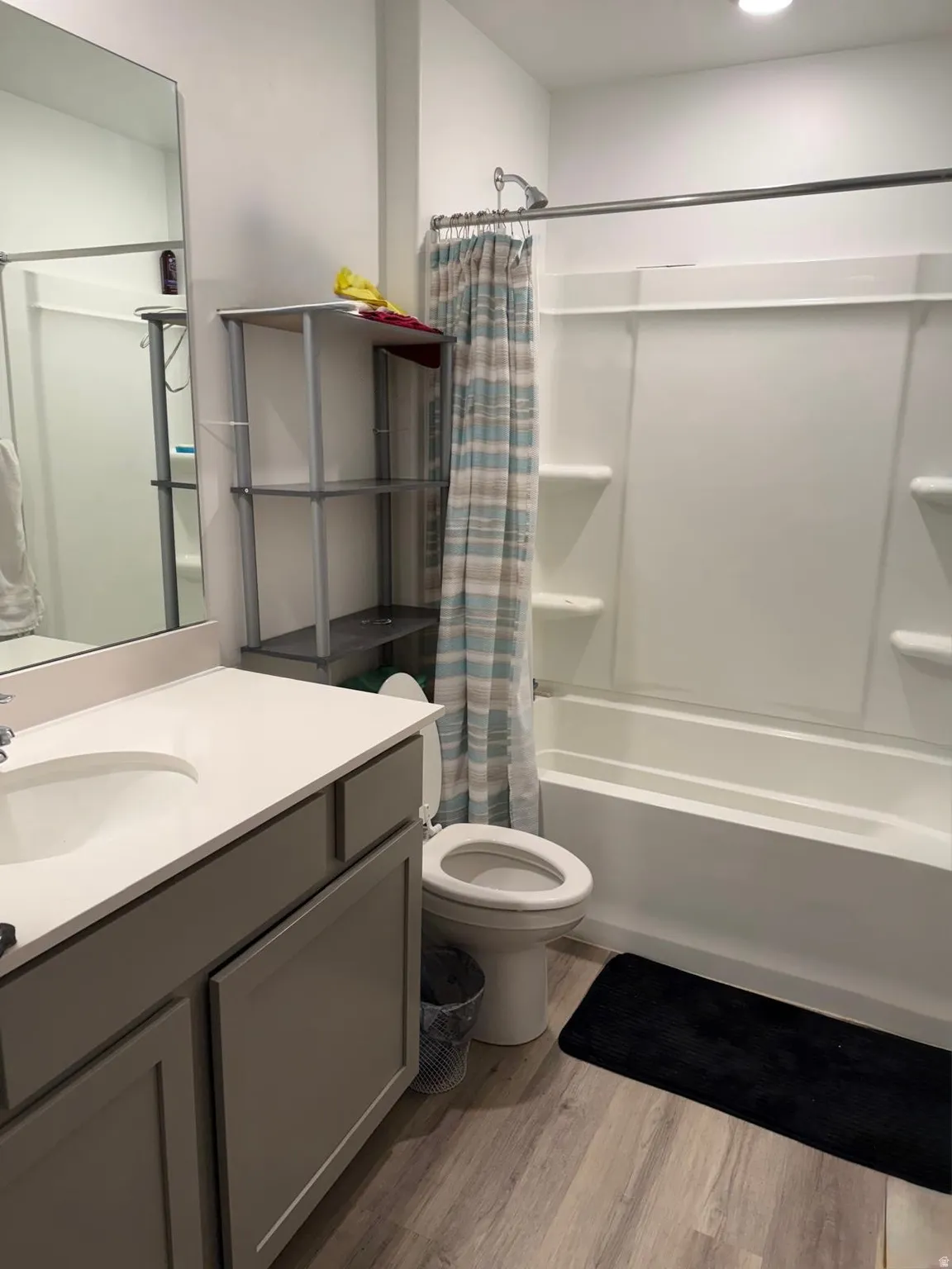 Bathroom featuring vanity, shower / bath combo with shower curtain, and light wood-type flooring