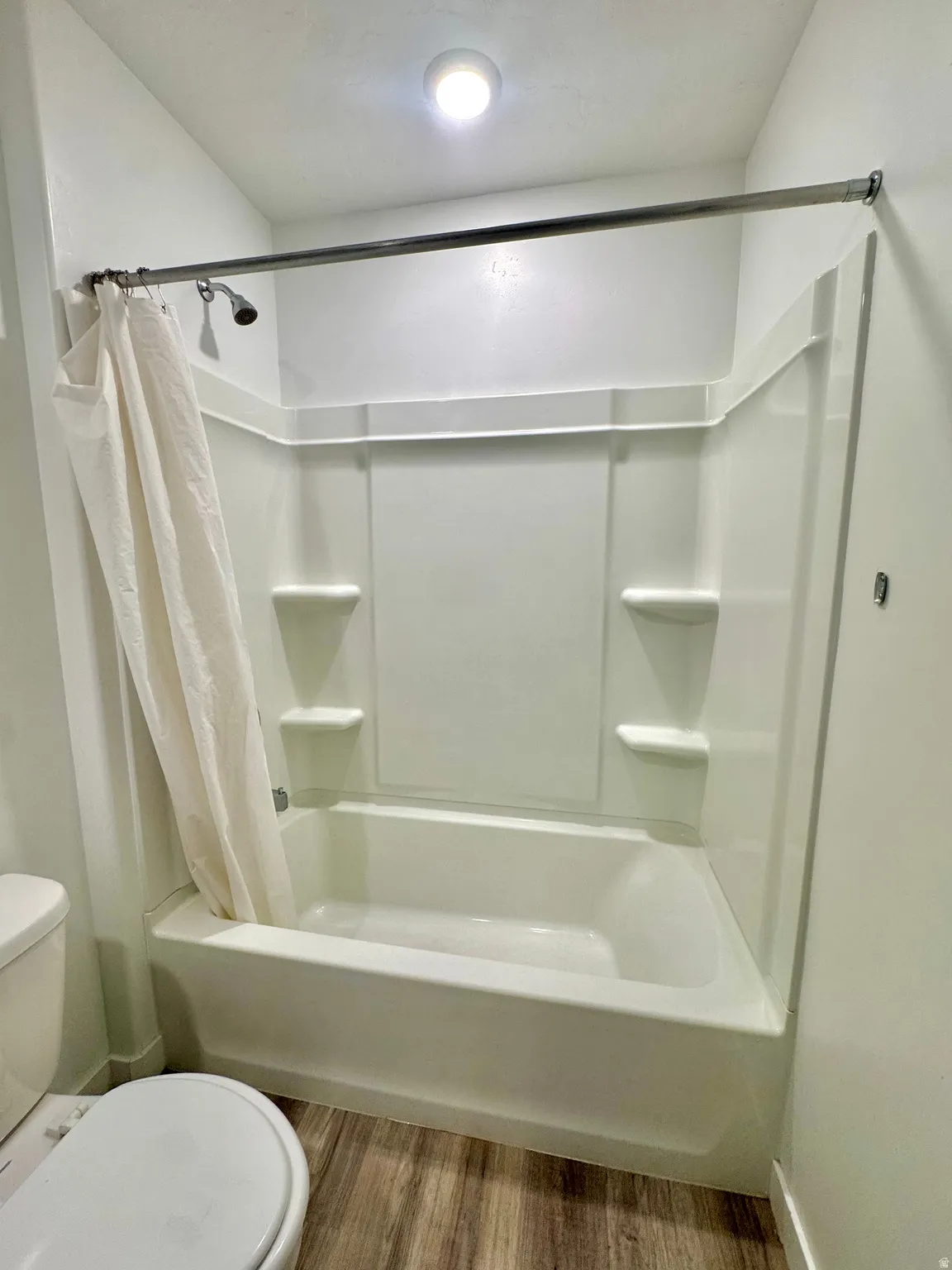 Bathroom with light wood-type flooring and shower / bath combo