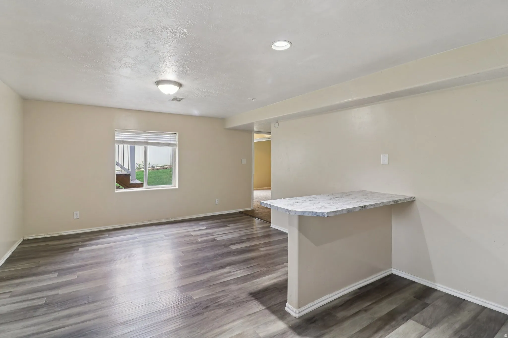 Unfurnished room featuring dark wood-type flooring and a textured ceiling