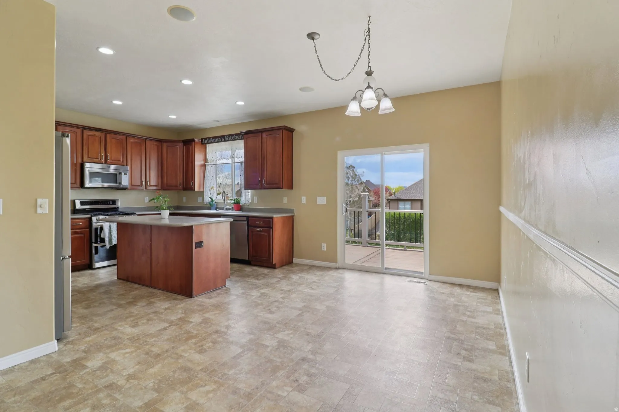 Kitchen with a kitchen island, stainless steel appliances, hanging lights, and light countertops