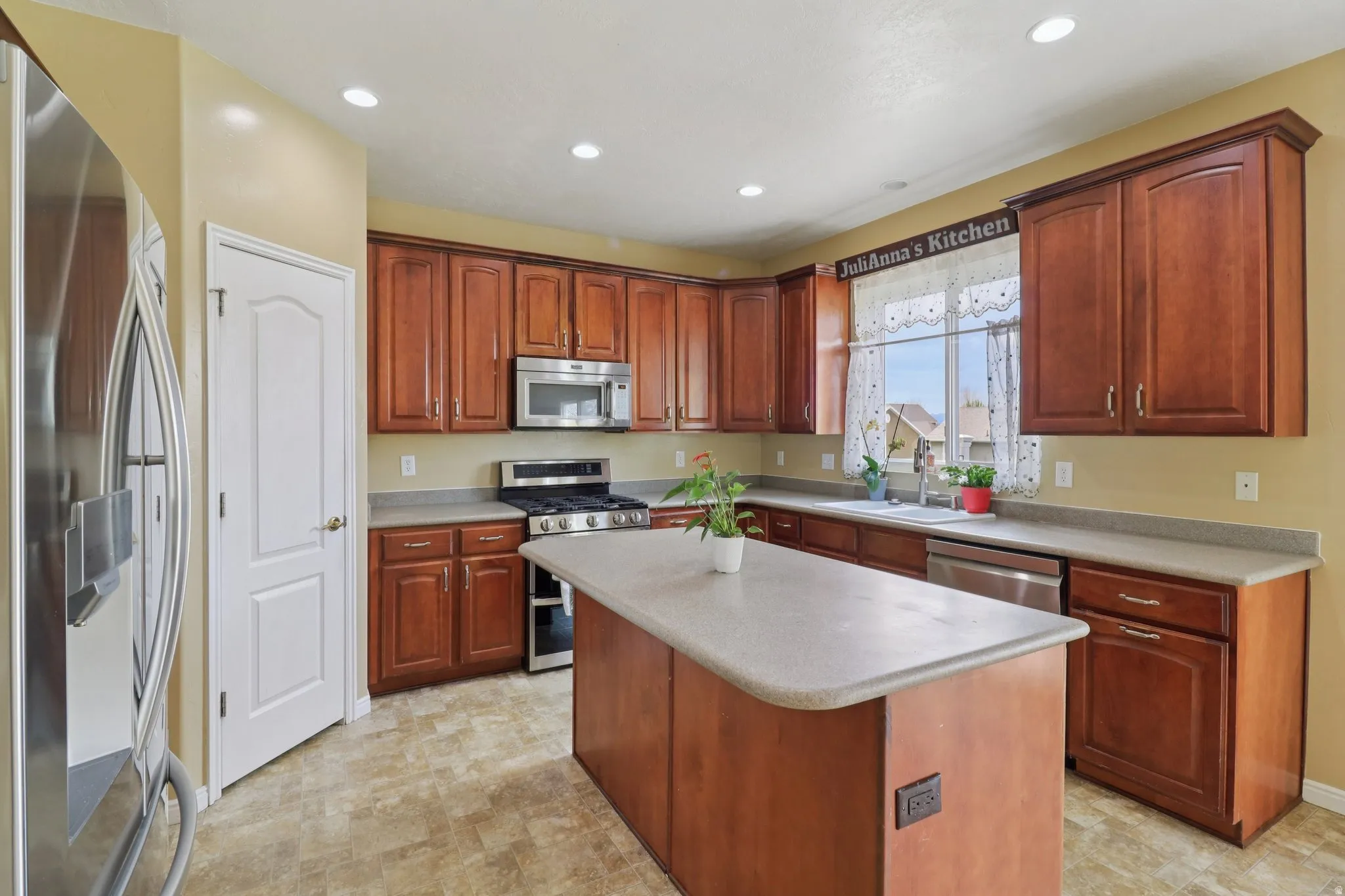 Kitchen featuring stainless steel appliances, a kitchen island, light countertops, and recessed lighting