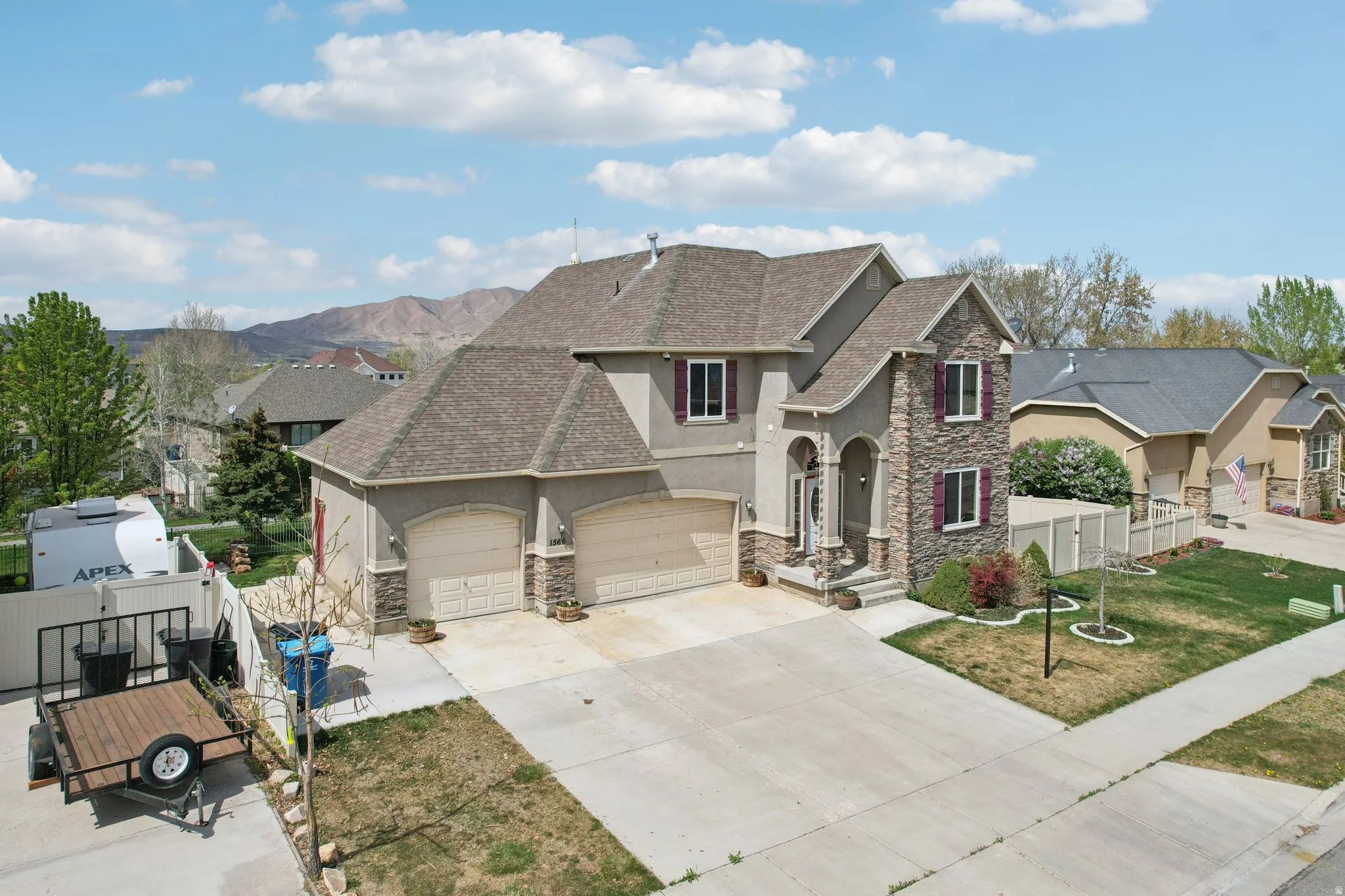 View of front of house featuring stucco siding, a shingled roof, stone siding, driveway, and a garage