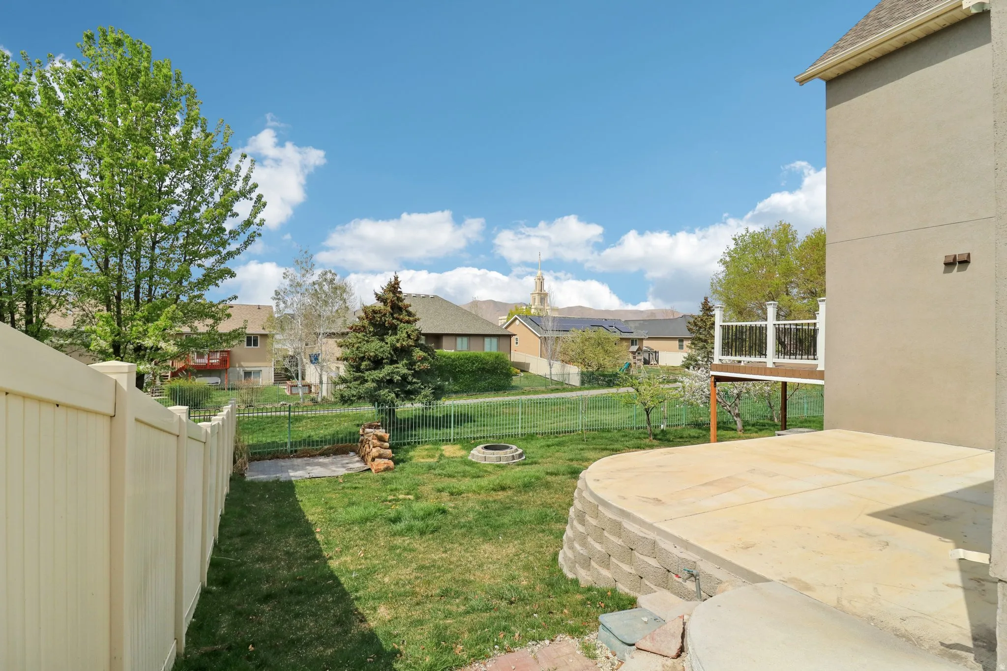 Fenced backyard featuring a fire pit, a residential view, and a patio area