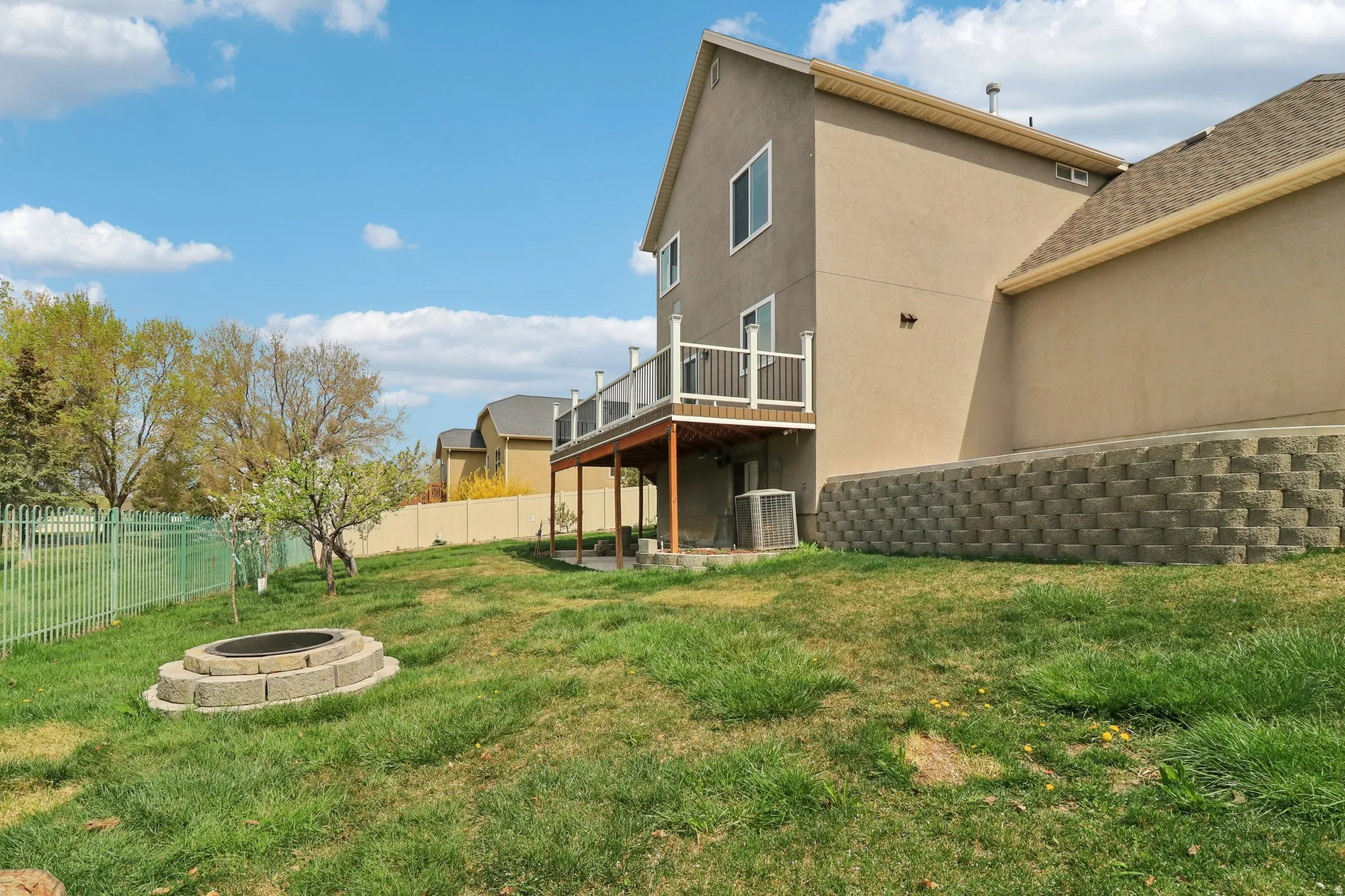 Fenced backyard featuring a patio area, a fire pit, and a wooden deck