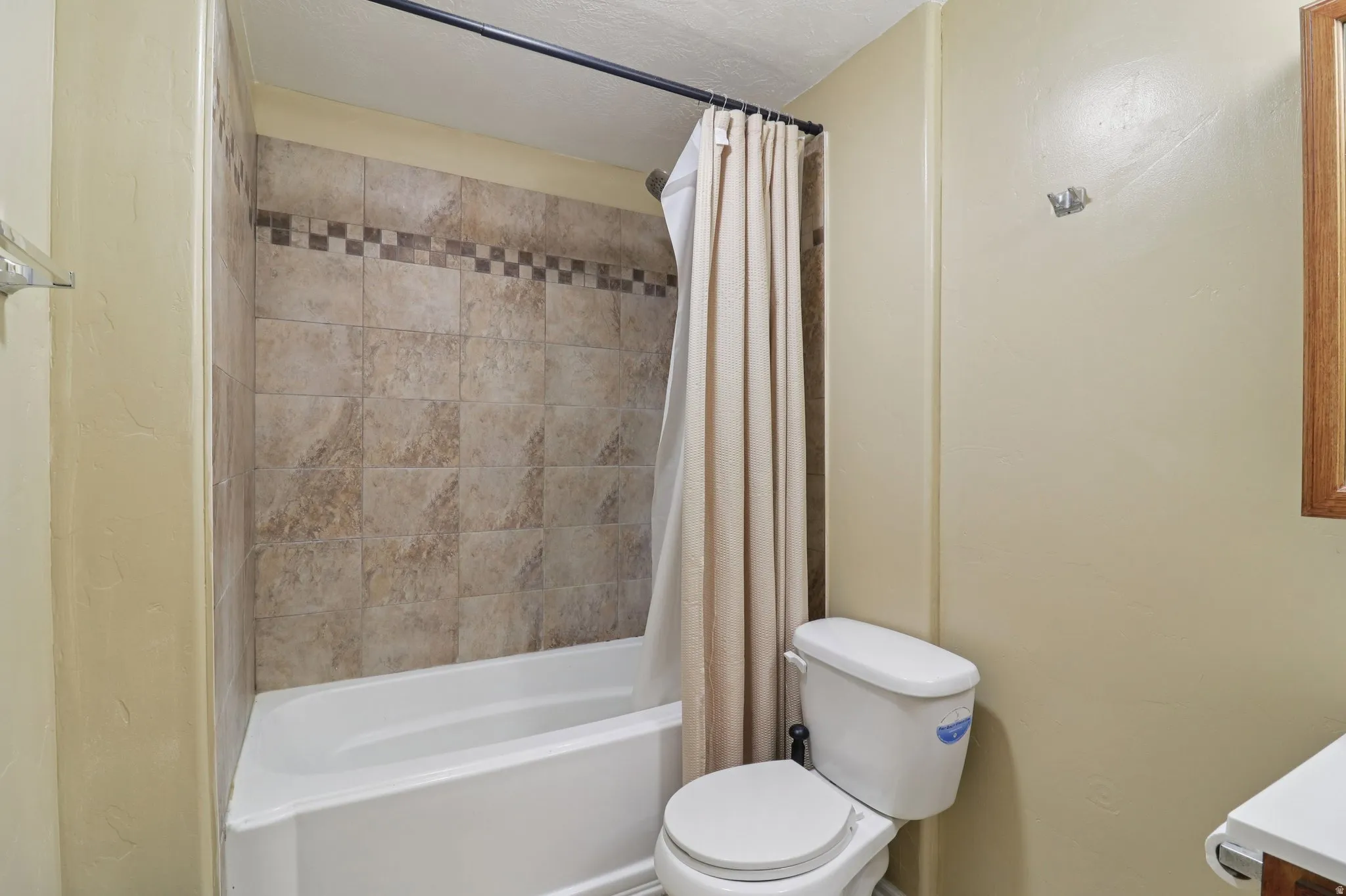 Bathroom featuring shower / tub combo with curtain, a textured ceiling, and vanity