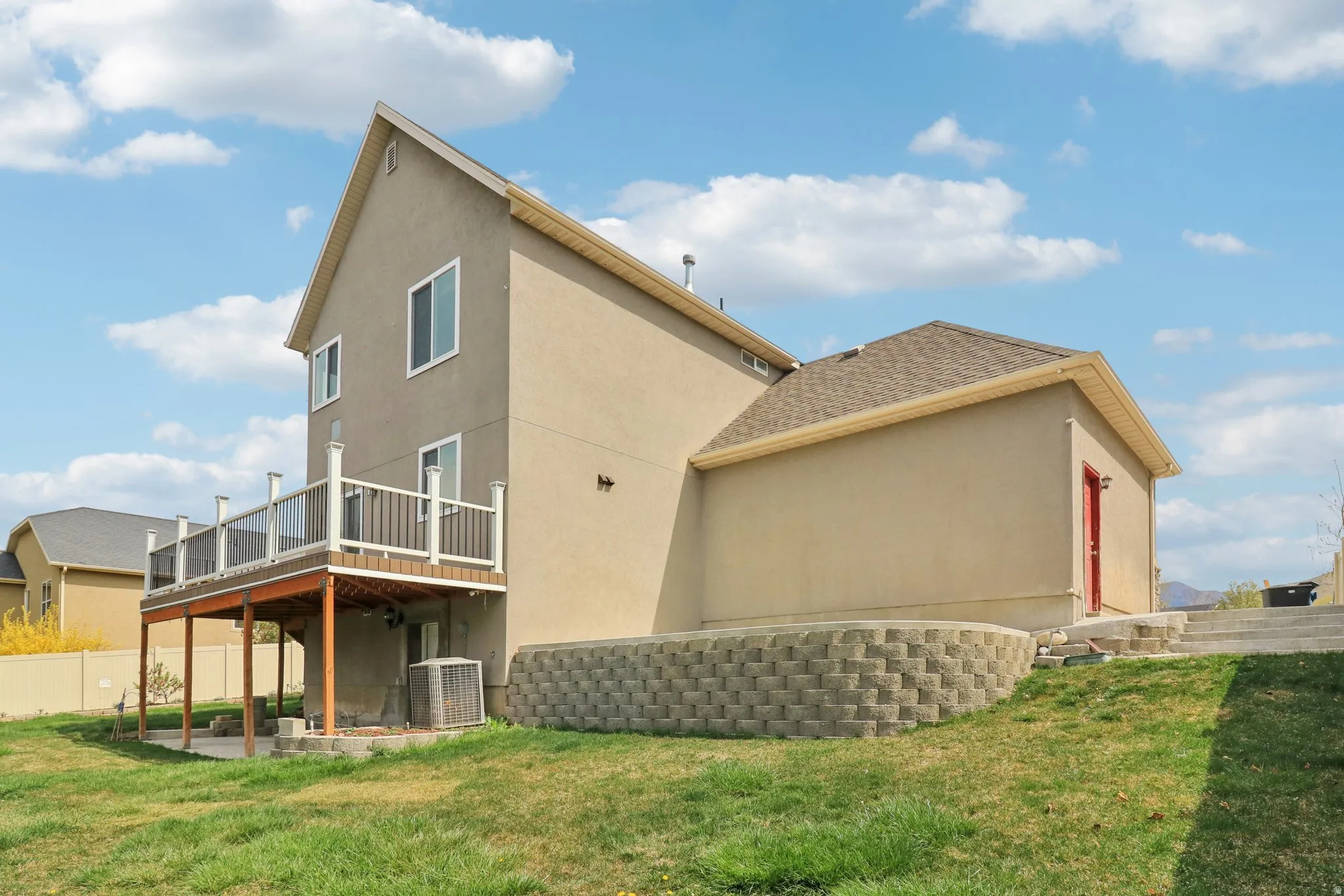 Rear view of property featuring a patio, stucco siding, and a wooden deck