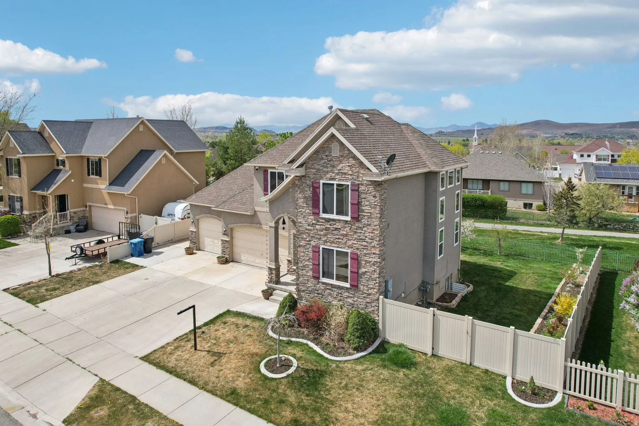 View of front of home with stone siding, stucco siding, driveway, a residential view, and a mountain view