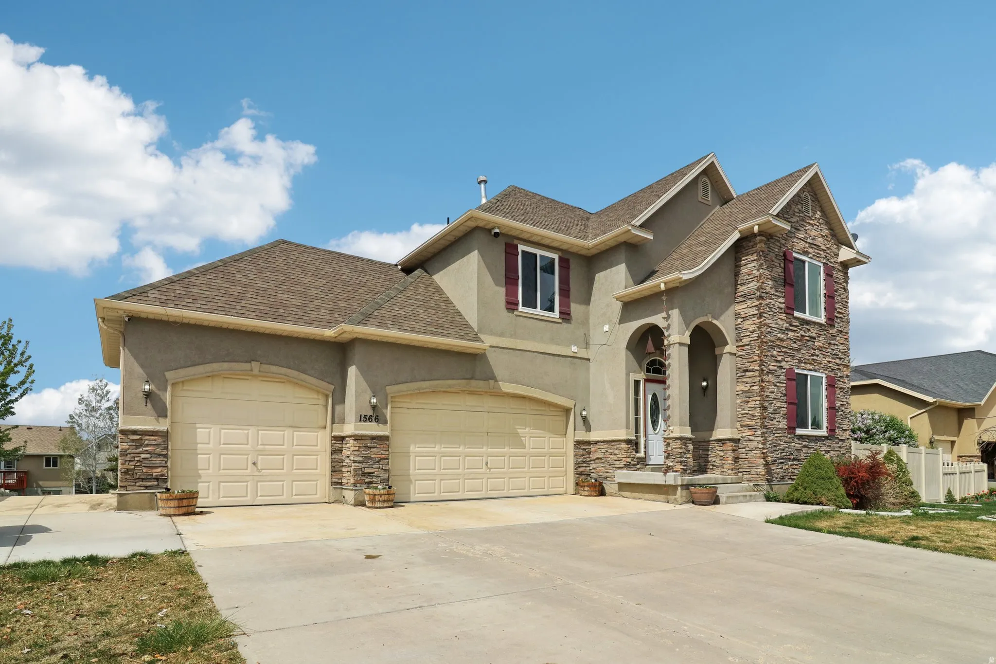 View of front of home featuring stucco siding, stone siding, driveway, and roof with shingles