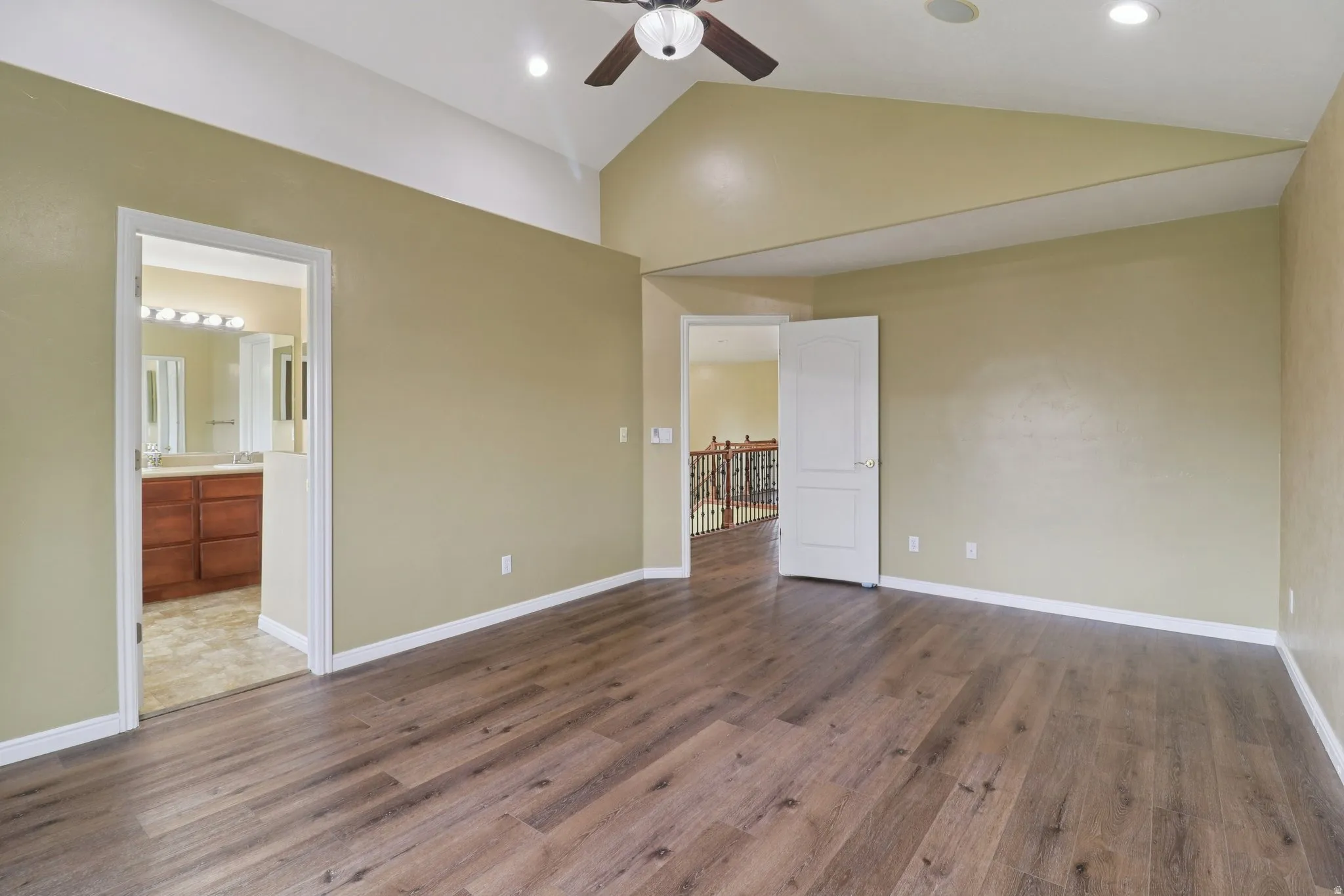 Unfurnished bedroom with vaulted ceiling, dark wood-style floors, recessed lighting, ceiling fan, and ensuite bathroom