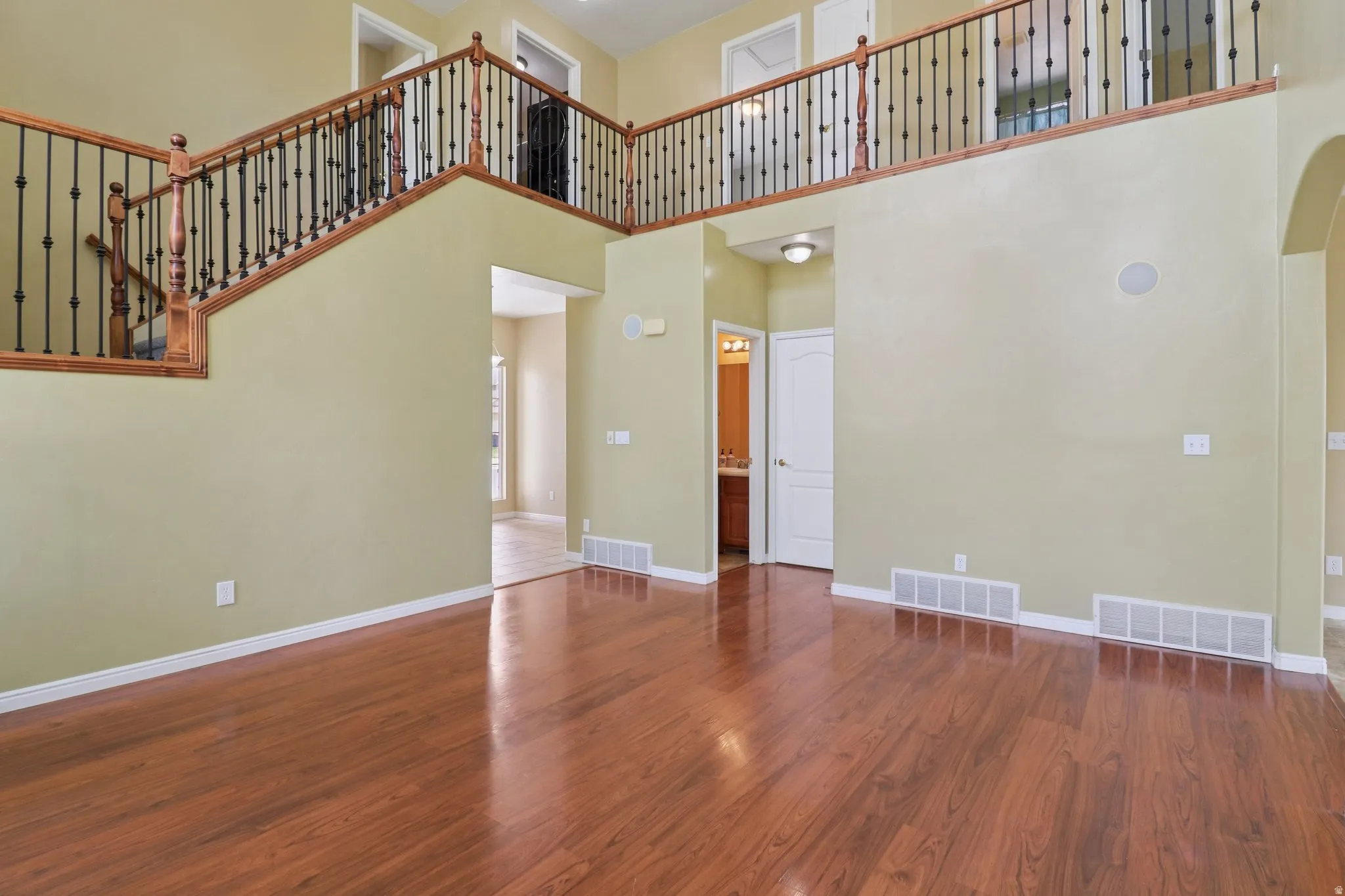 Unfurnished living room with dark wood-style flooring, arched walkways, and a high ceiling
